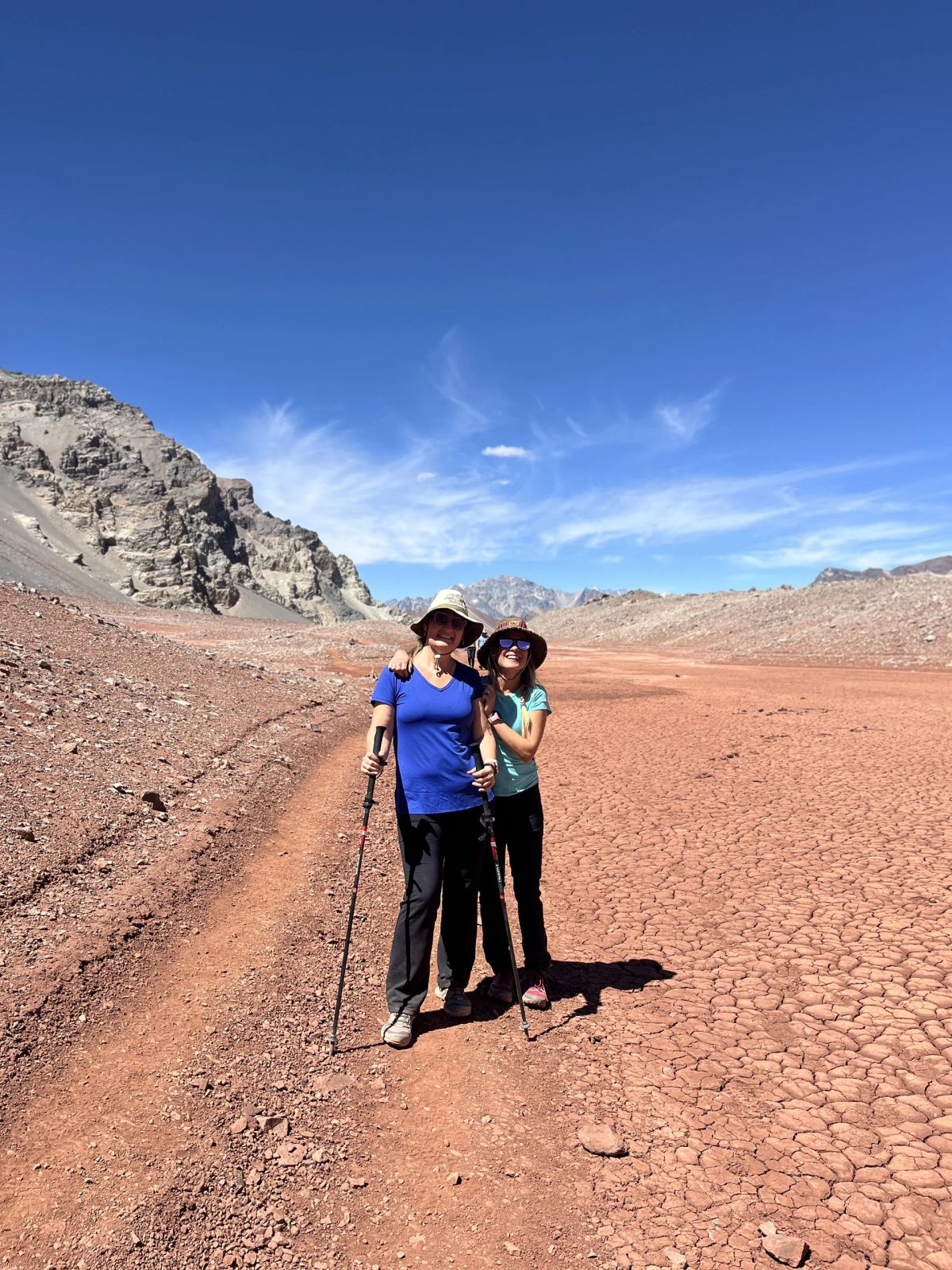Dos trekkers abrazados sobre el barro agrietado del valle de Horcones