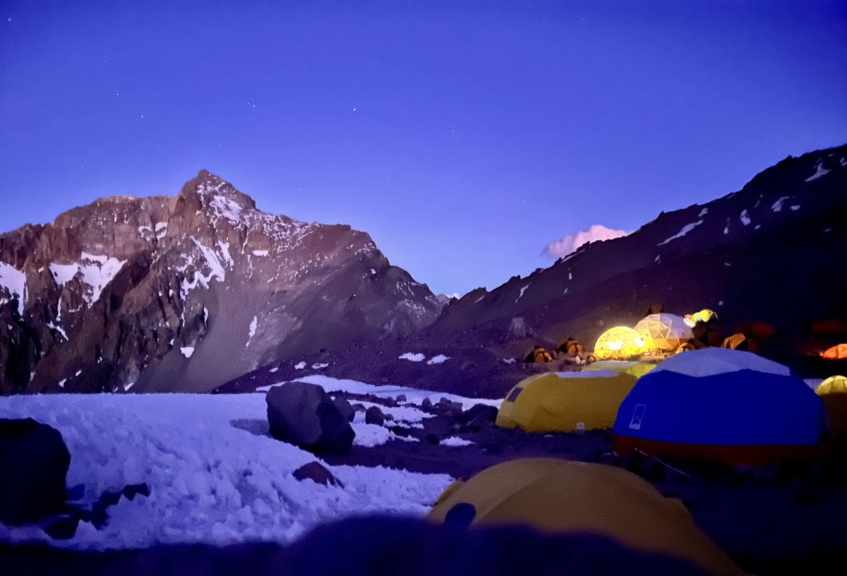 Carpas iluminadas al anochecer en el campamento de altura del Aconcagua