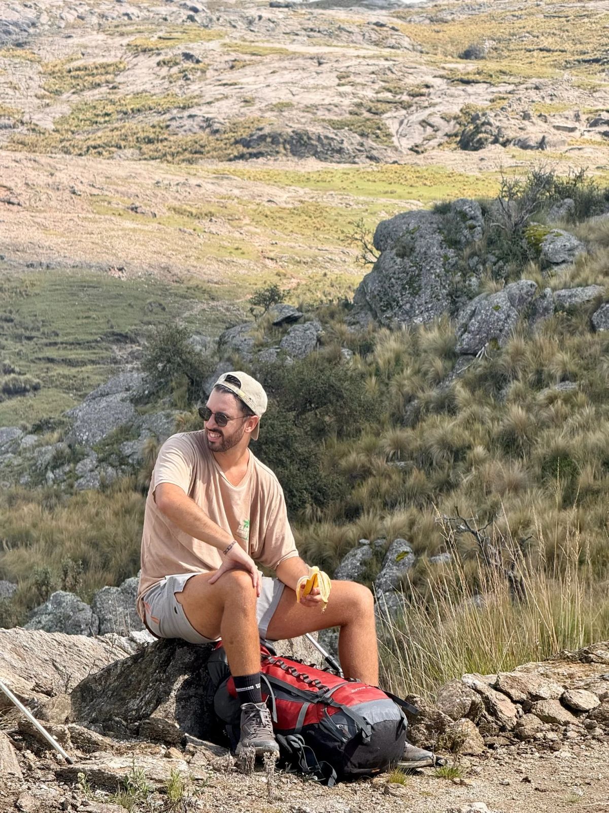 Trekker sentado sobre una roca junto a su mochila durante una pausa en el ascenso al Champaquí
