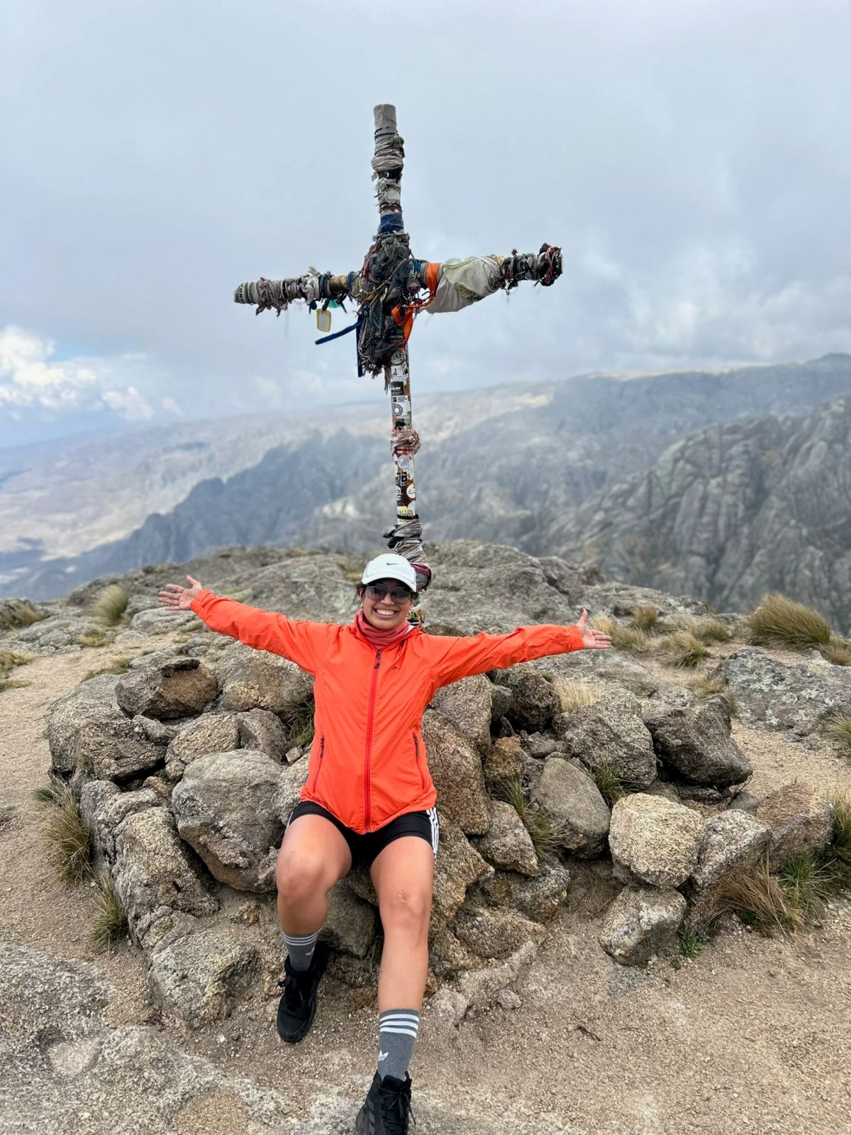 Trekker con los brazos abiertos junto a la cruz cumbrera de Los Gigantes tras alcanzar la cima