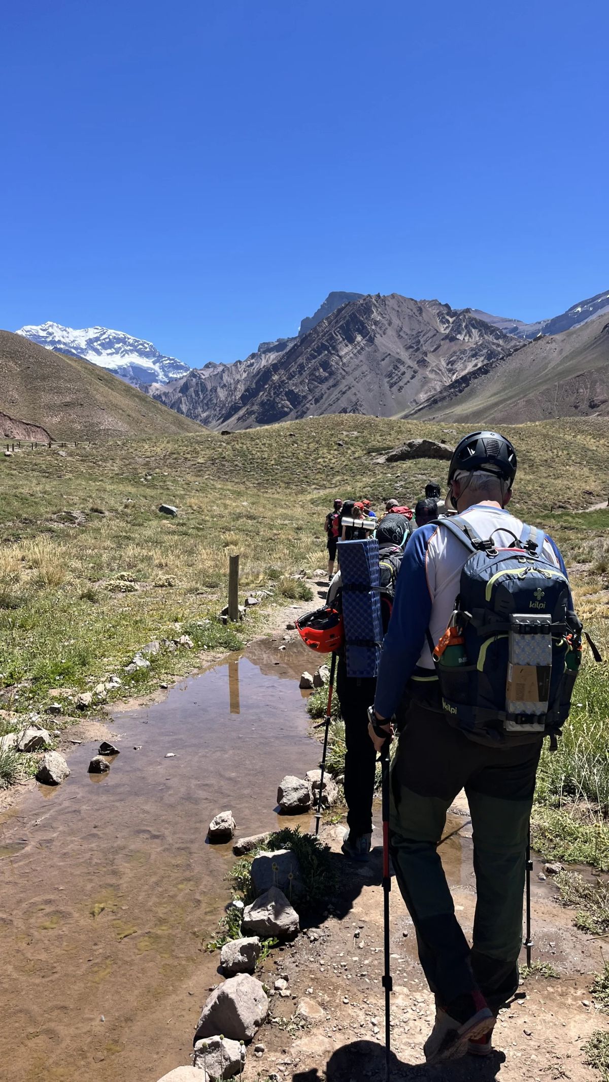 Trekker cruzando un arroyo de deshielo al comienzo del valle de Horcones