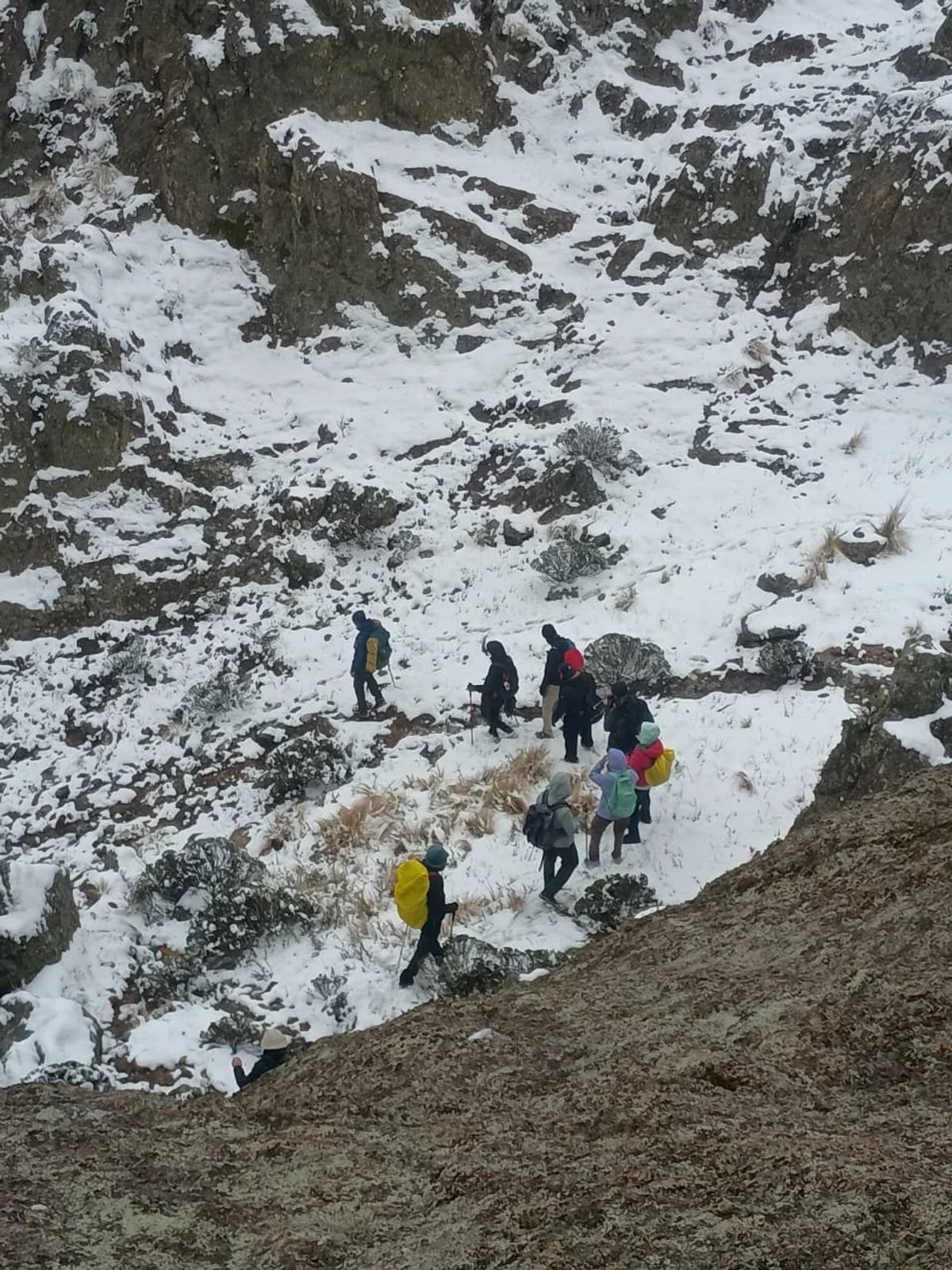 Fila de caminantes subiendo por la ladera nevada de Los Gigantes, Sierras Grandes de Córdoba