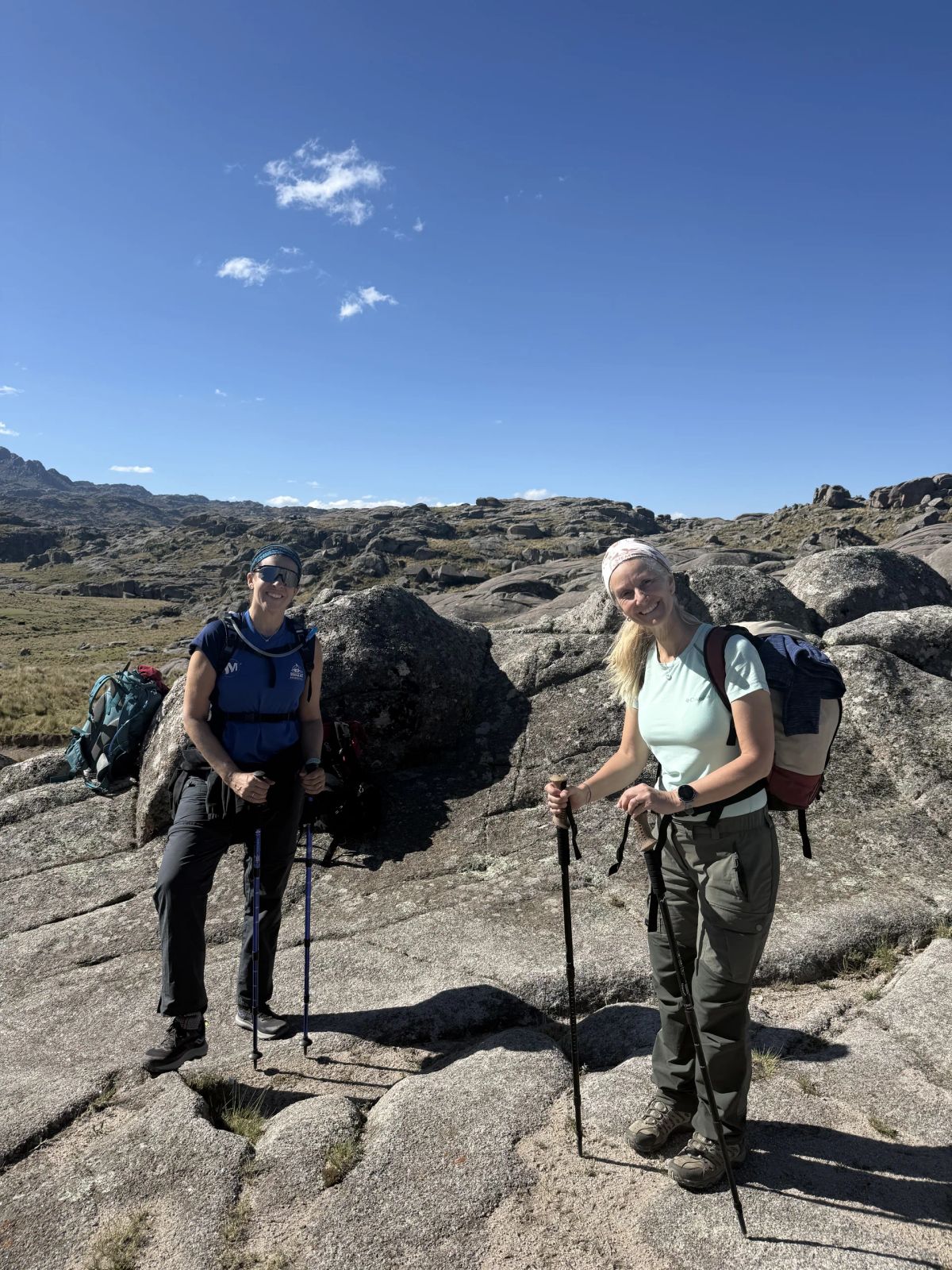 Dos trekkers con mochila y bastones sobre las lajas de granito del Champaquí