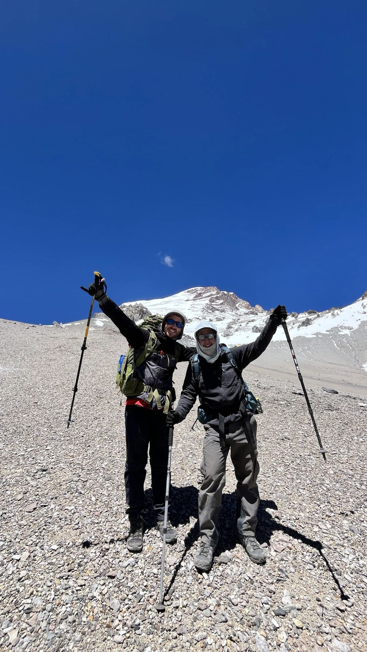 Dos andinistas celebrando durante un porteo con el Aconcagua de fondo
