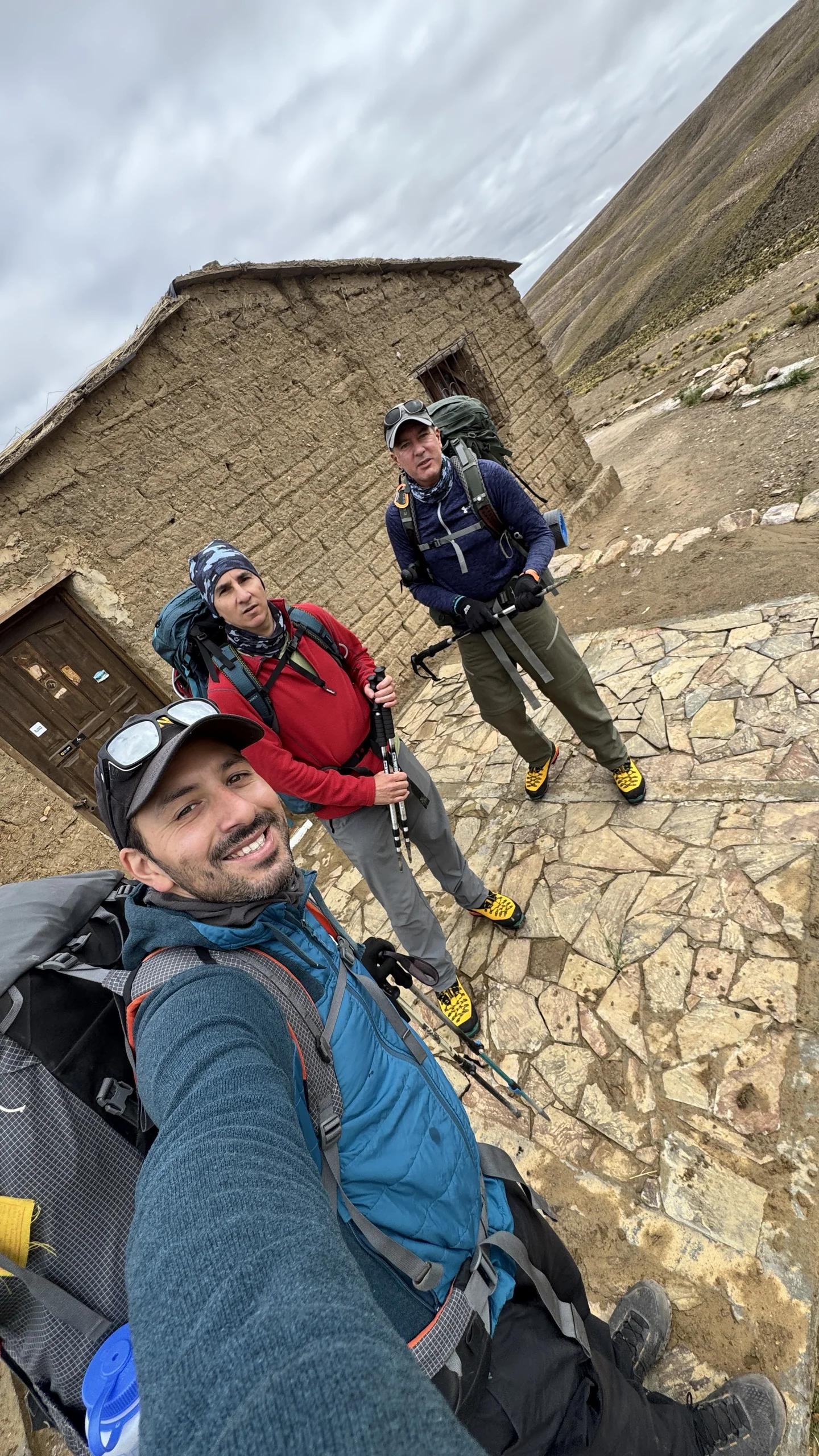 El equipo con las mochilas de expedición junto al refugio de piedra de la puna