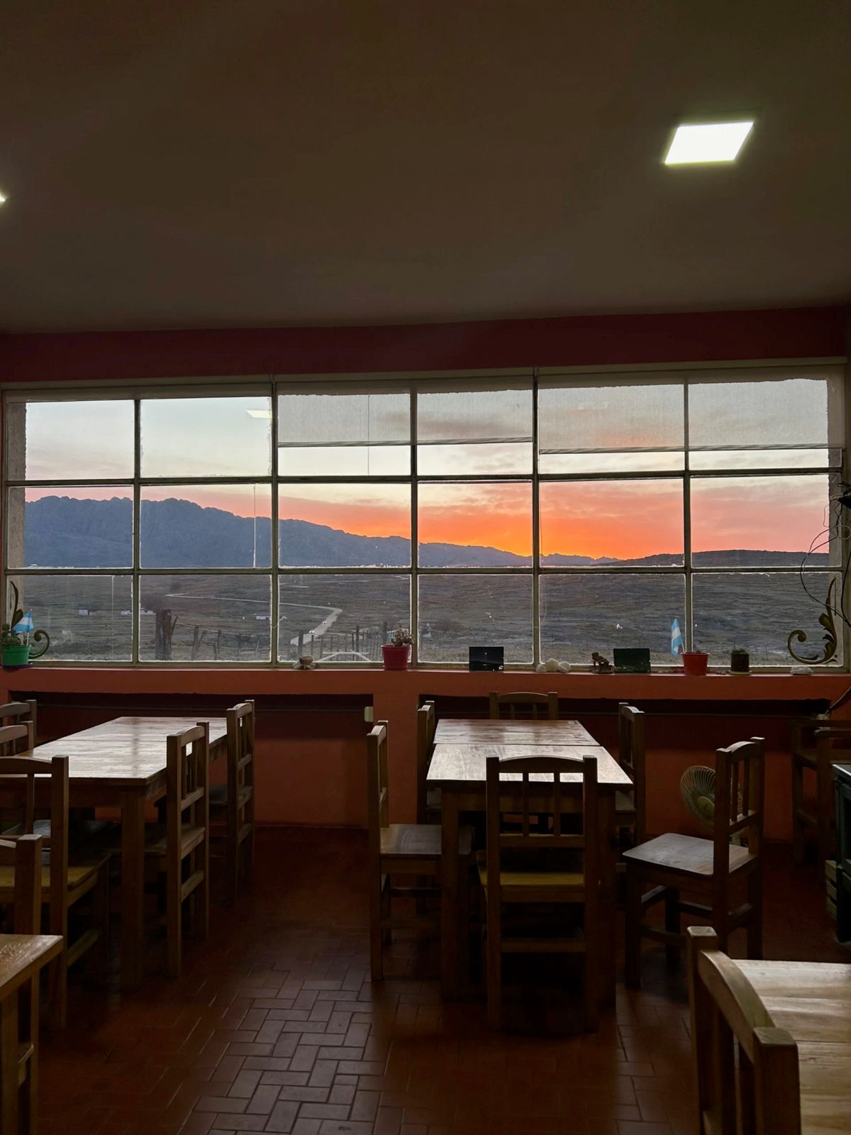 Comedor del refugio de Los Gigantes con el atardecer sobre las sierras a través del ventanal