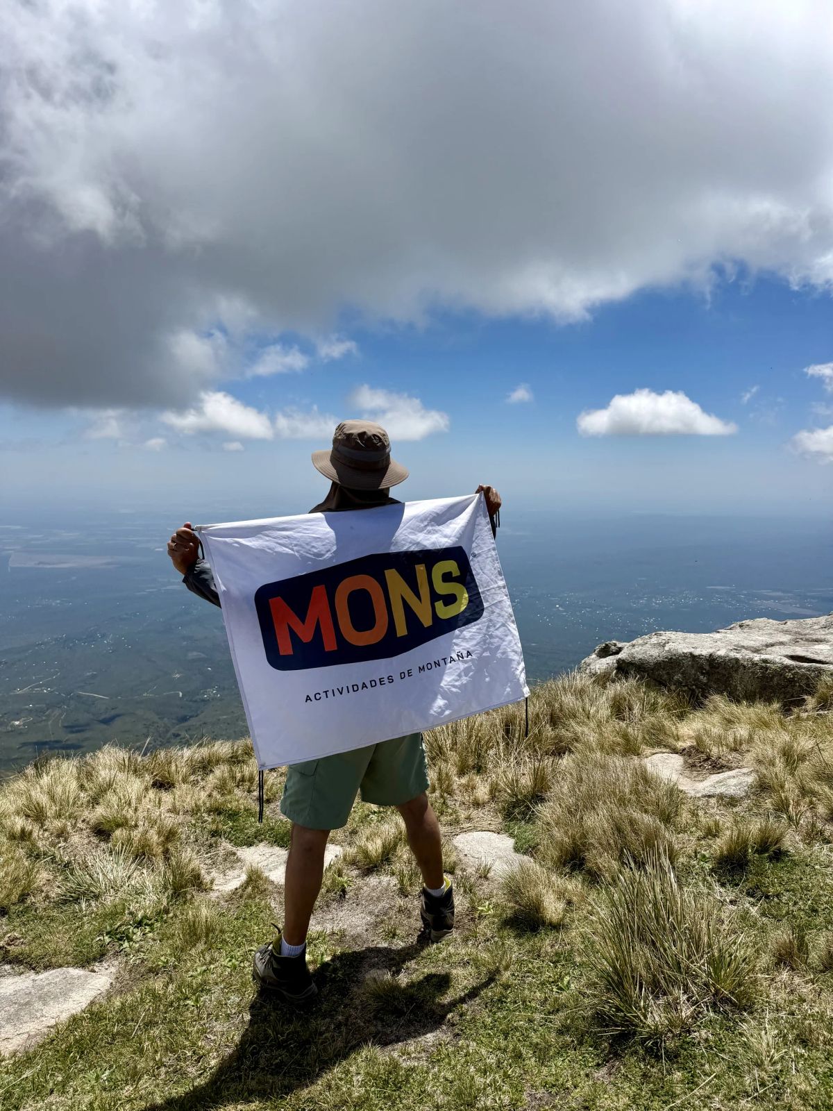 Participante desplegando la bandera de Mons en lo alto del Cerro Champaquí