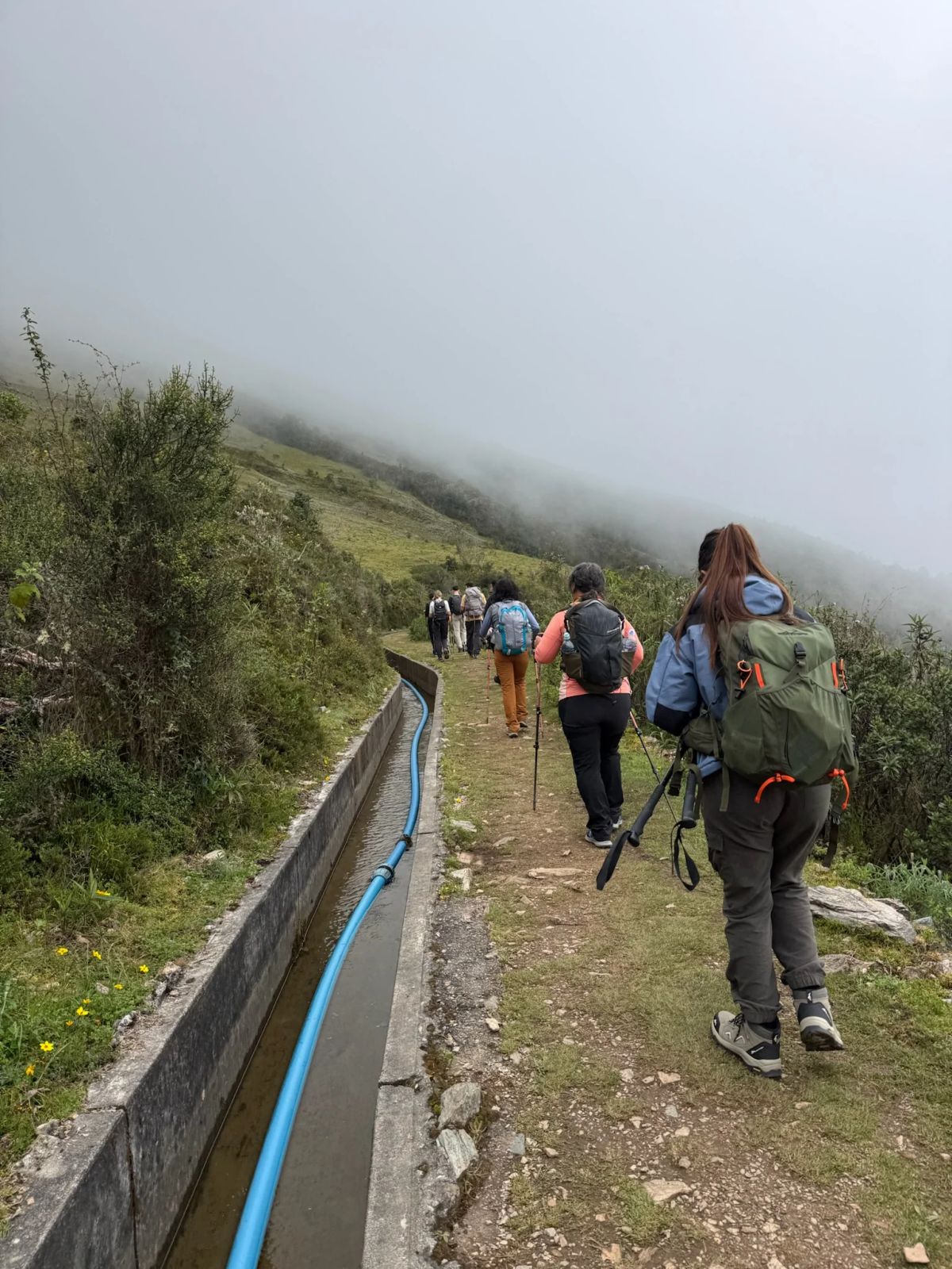 Caminantes avanzando junto al canal de riego en el valle del Salkantay