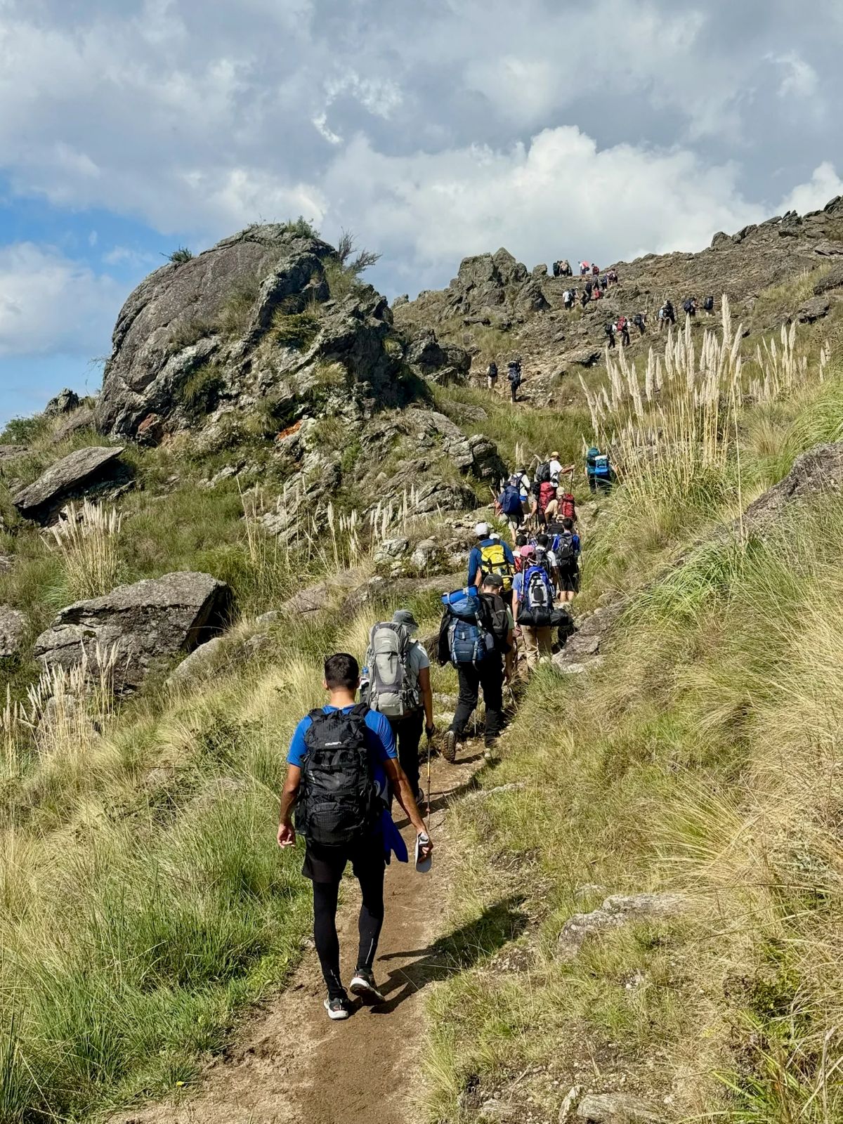Fila de caminantes ascendiendo por el sendero rocoso hacia el filo del Cerro Champaquí