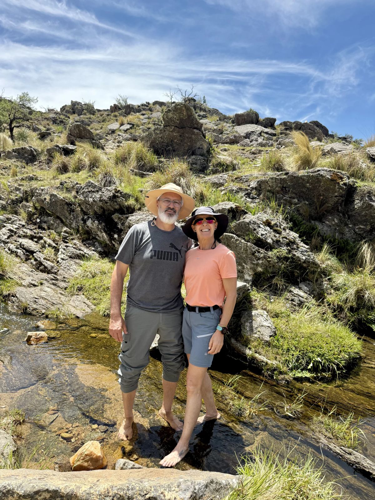 Dos participantes de la Salida 194 refrescándose en un arroyo de la pampa de altura