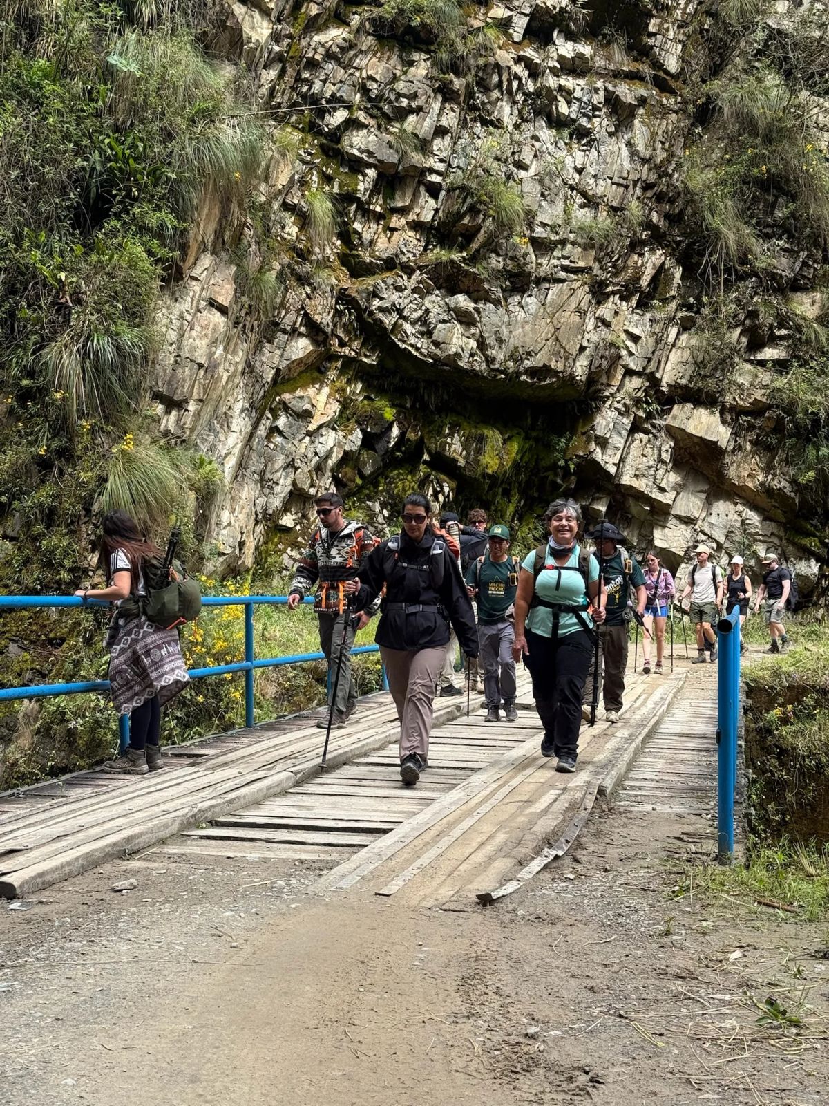 Trekkers cruzando un puente de madera sobre el río en la ruta del Salkantay