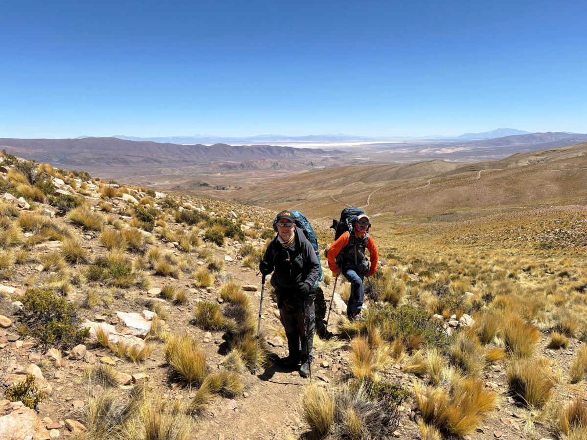 Dos montañistas avanzando por la puna jujeña con mochilas de expedición rumbo al Chañi
