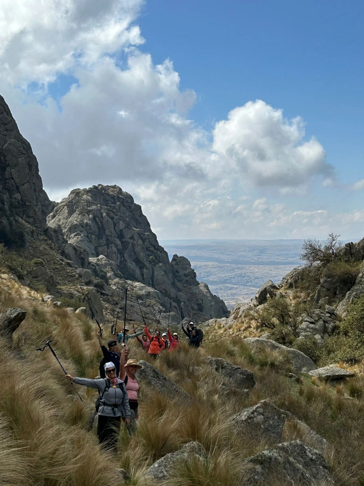 Fila de caminantes por el sendero entre pajonales de Los Gigantes, con las paredes de granito al frente