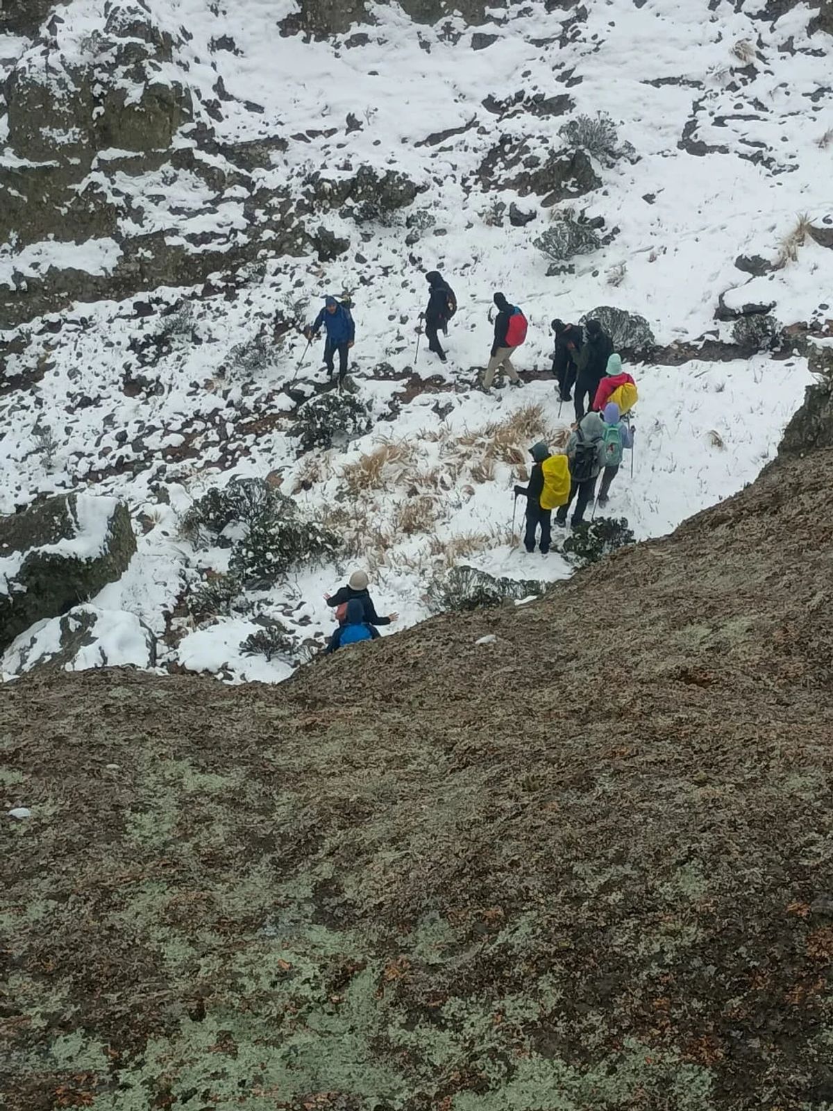 Grupo de caminantes cruzando una ladera nevada de las Sierras Grandes