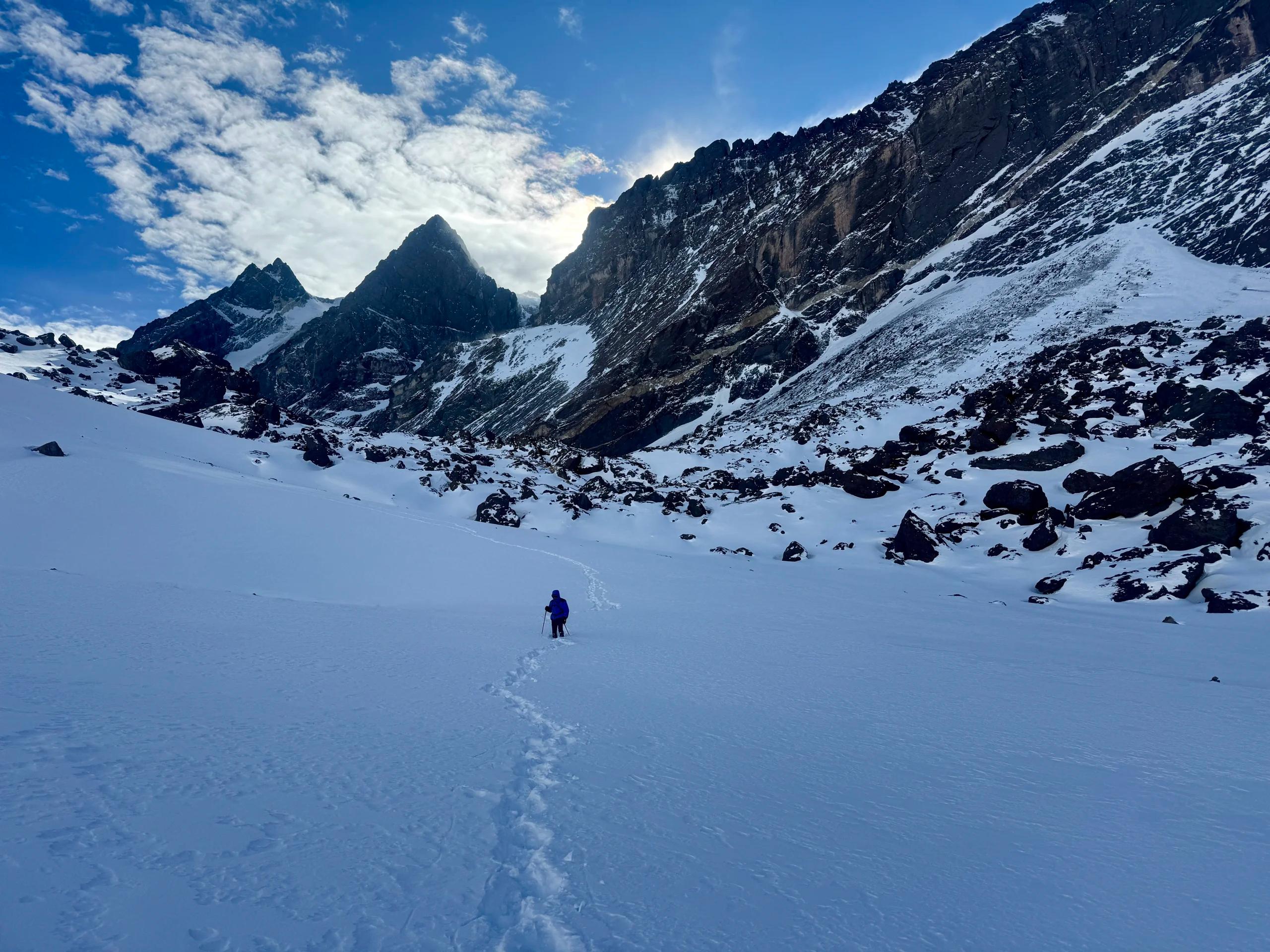 Agujas de roca del Cerro Mirador del Tolosa sobre el circo nevado, con un andinista de Mons abriendo huella durante el ascenso invernal en Mendoza