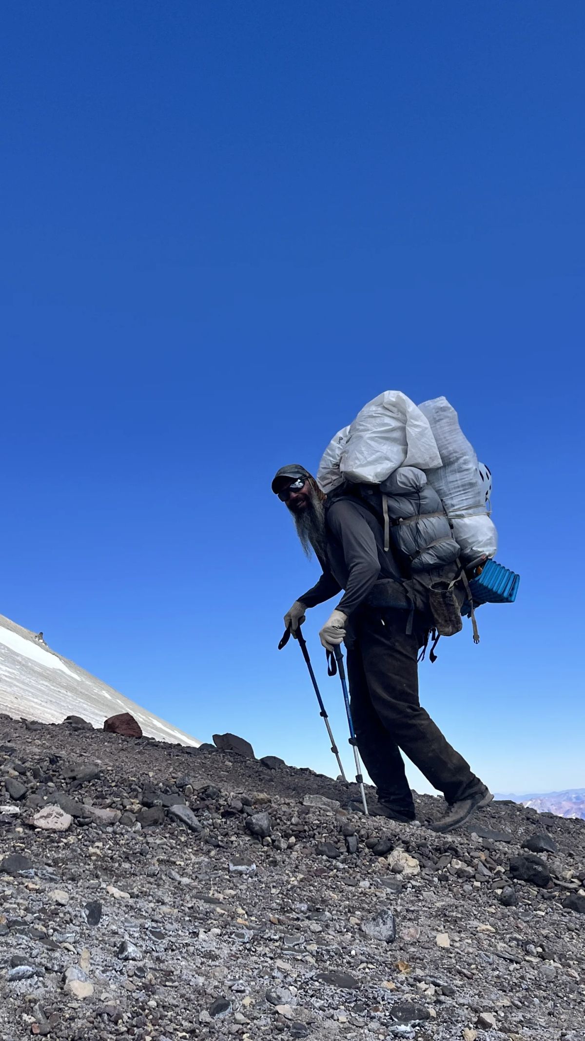 Andinista con mochila de porteo recortado contra el cielo en la ruta al Aconcagua