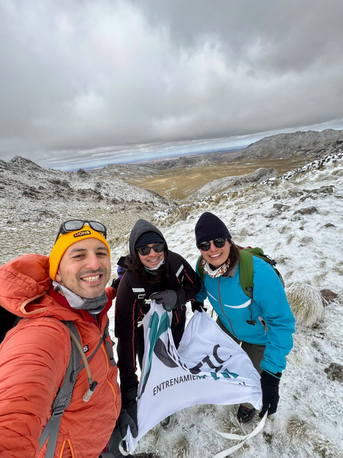 Selfie de tres participantes de Mons con la nieve del Cerro El Morro de fondo