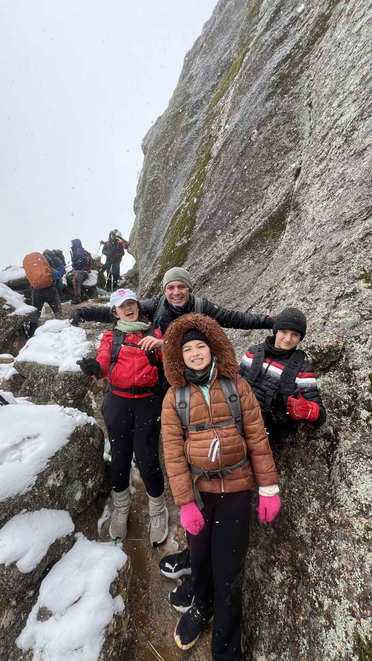 Participantes posando en un paso estrecho entre bloques de granito con nieve