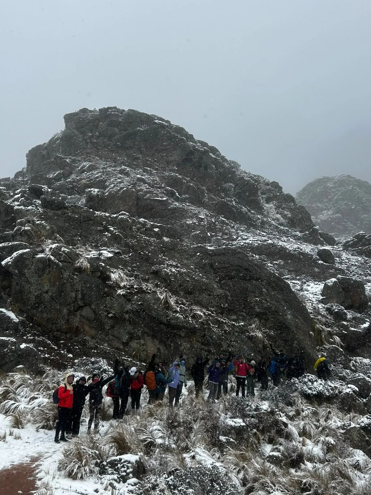 Columna de trekkers al pie de un mogote de granito cubierto de nieve