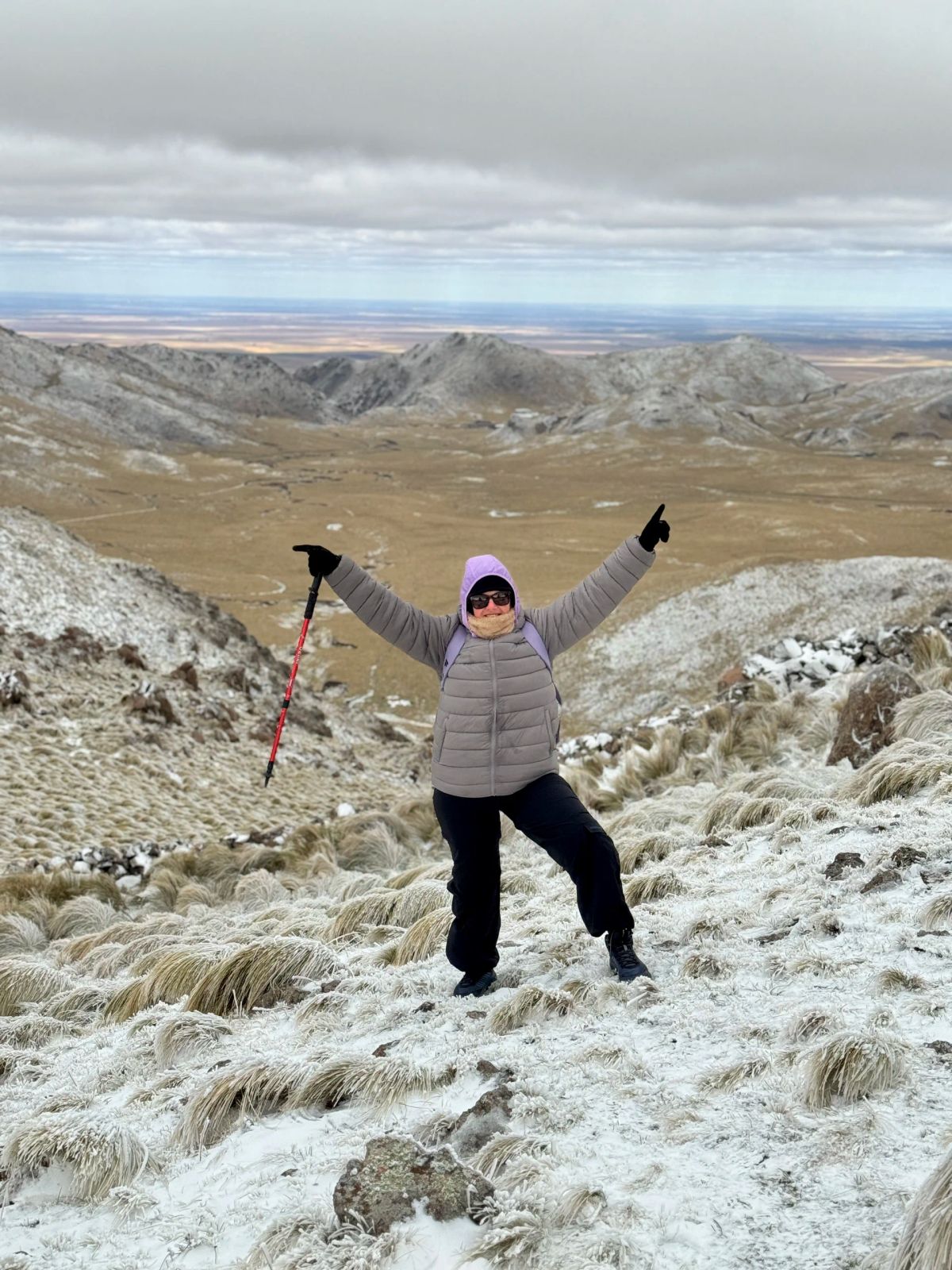 Trekker celebrando con los bastones en alto en la ladera nevada del Cerro El Morro