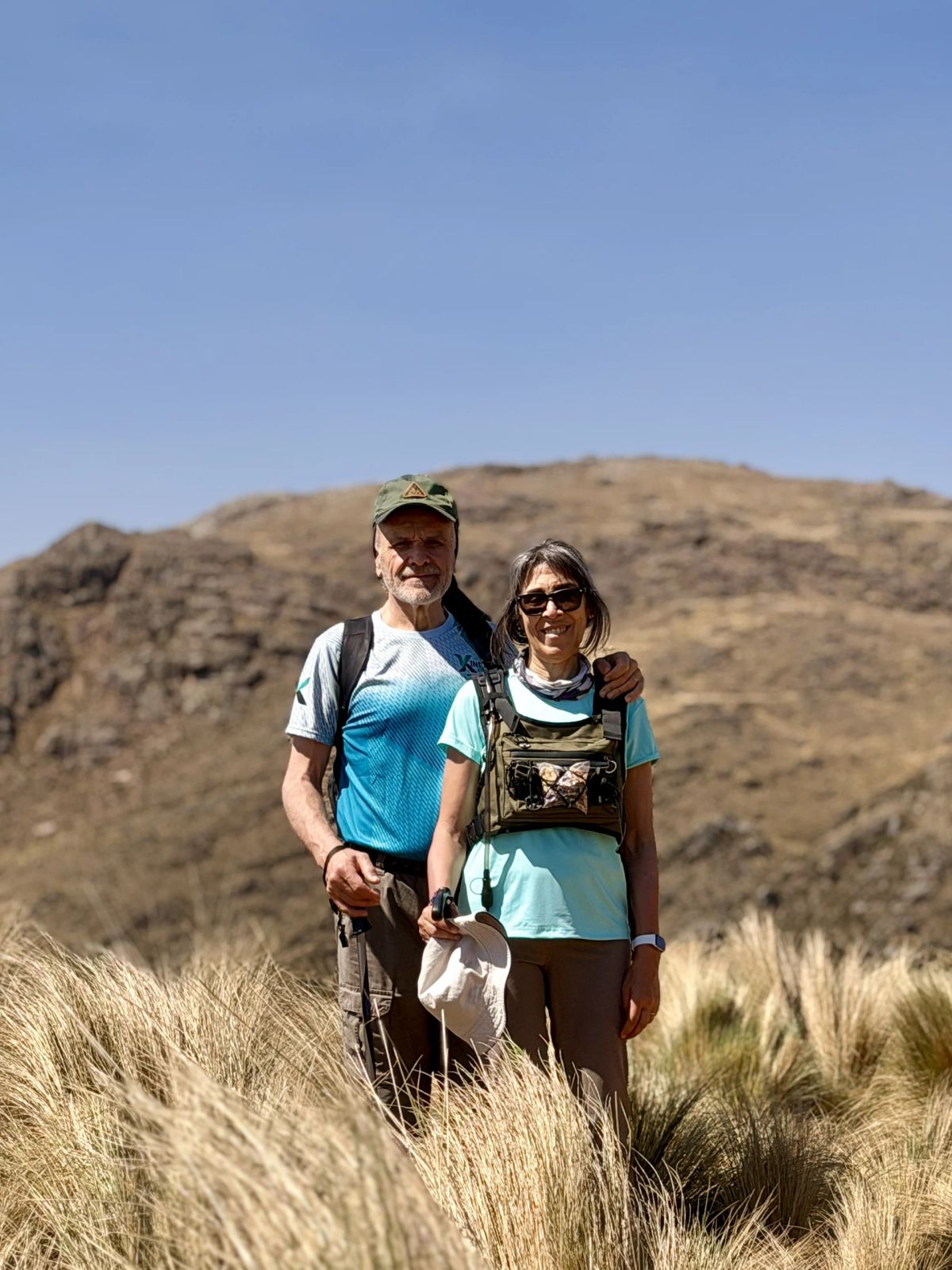 Dos trekkers entre los pajonales dorados con el cordón serrano al fondo