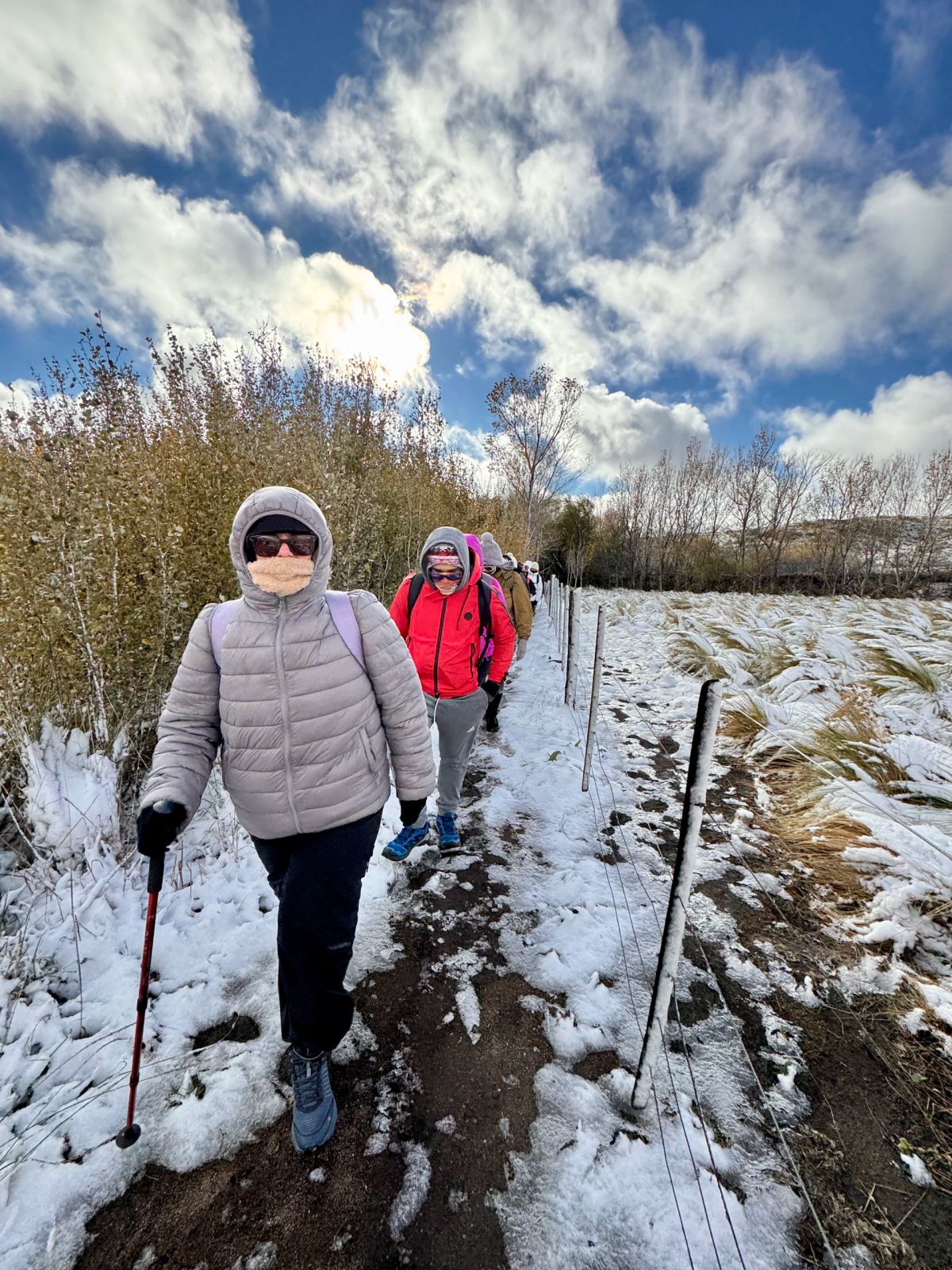 Dos trekkers con bastones avanzando por el sendero nevado del Cerro El Morro