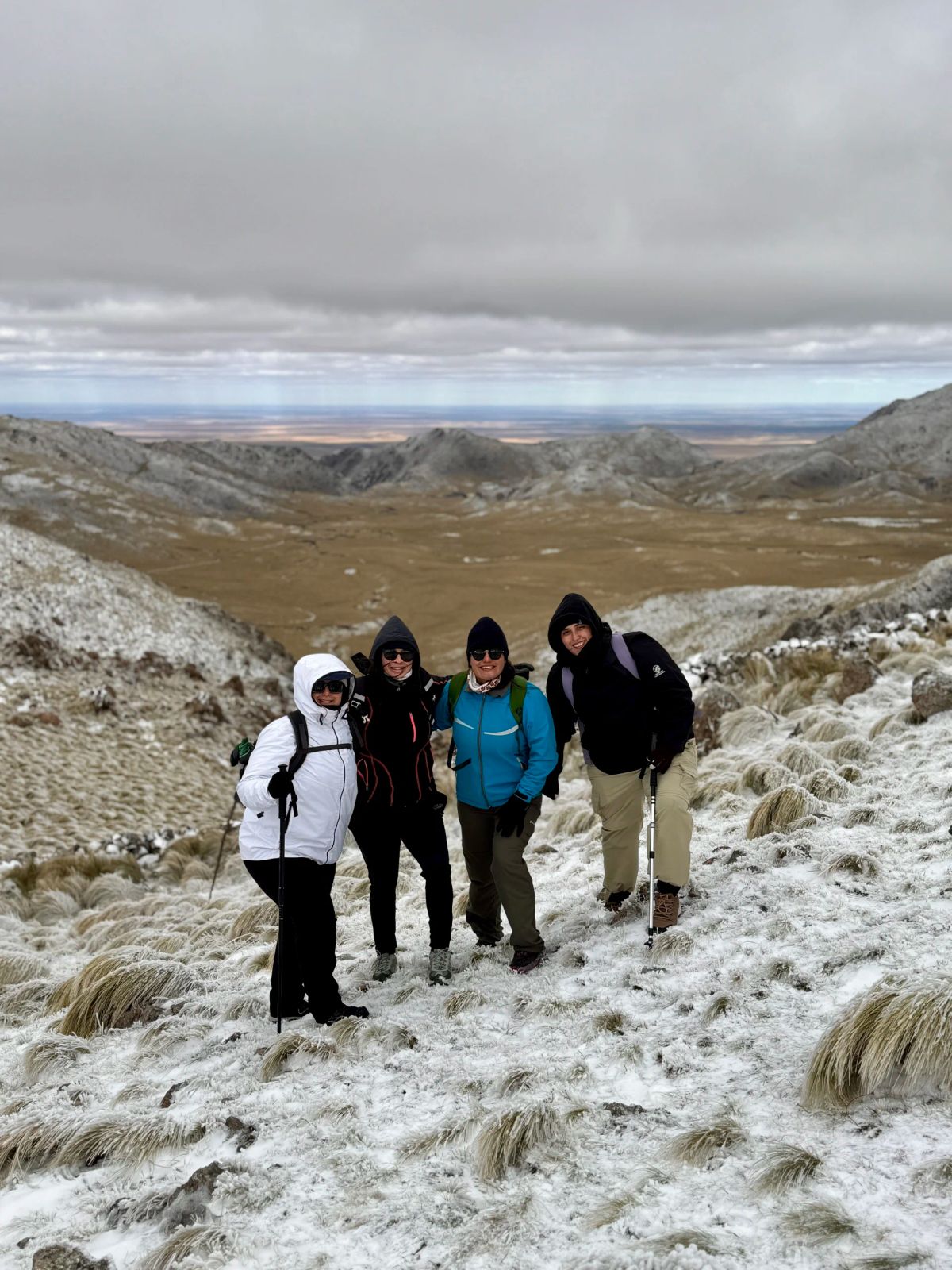 Grupo posando en el sendero con los pastizales nevados y la llanura puntana detrás