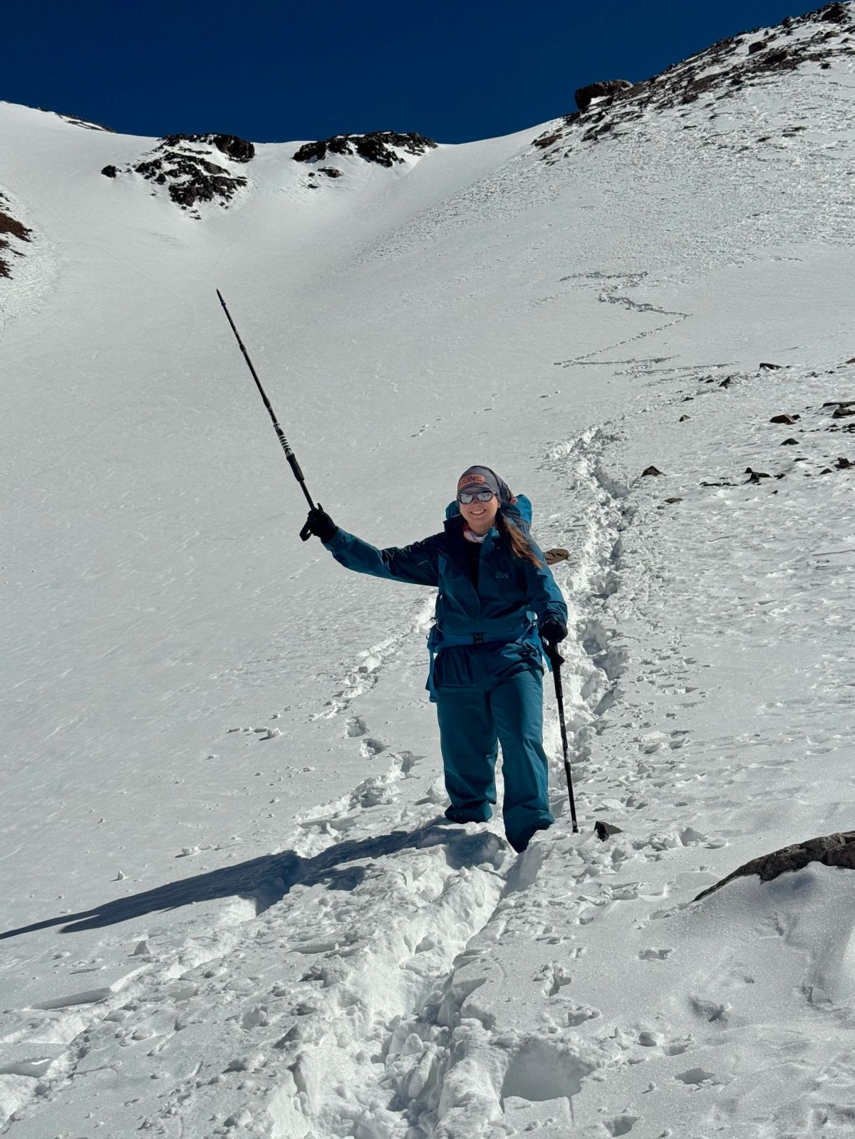 Andinista celebrando con el bastón en alto en la nieve profunda del Cordón del Plata