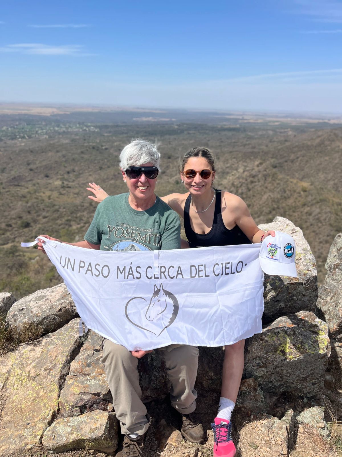 Dos participantes de Mons con una bandera en lo alto del cerro de Alpa Corral