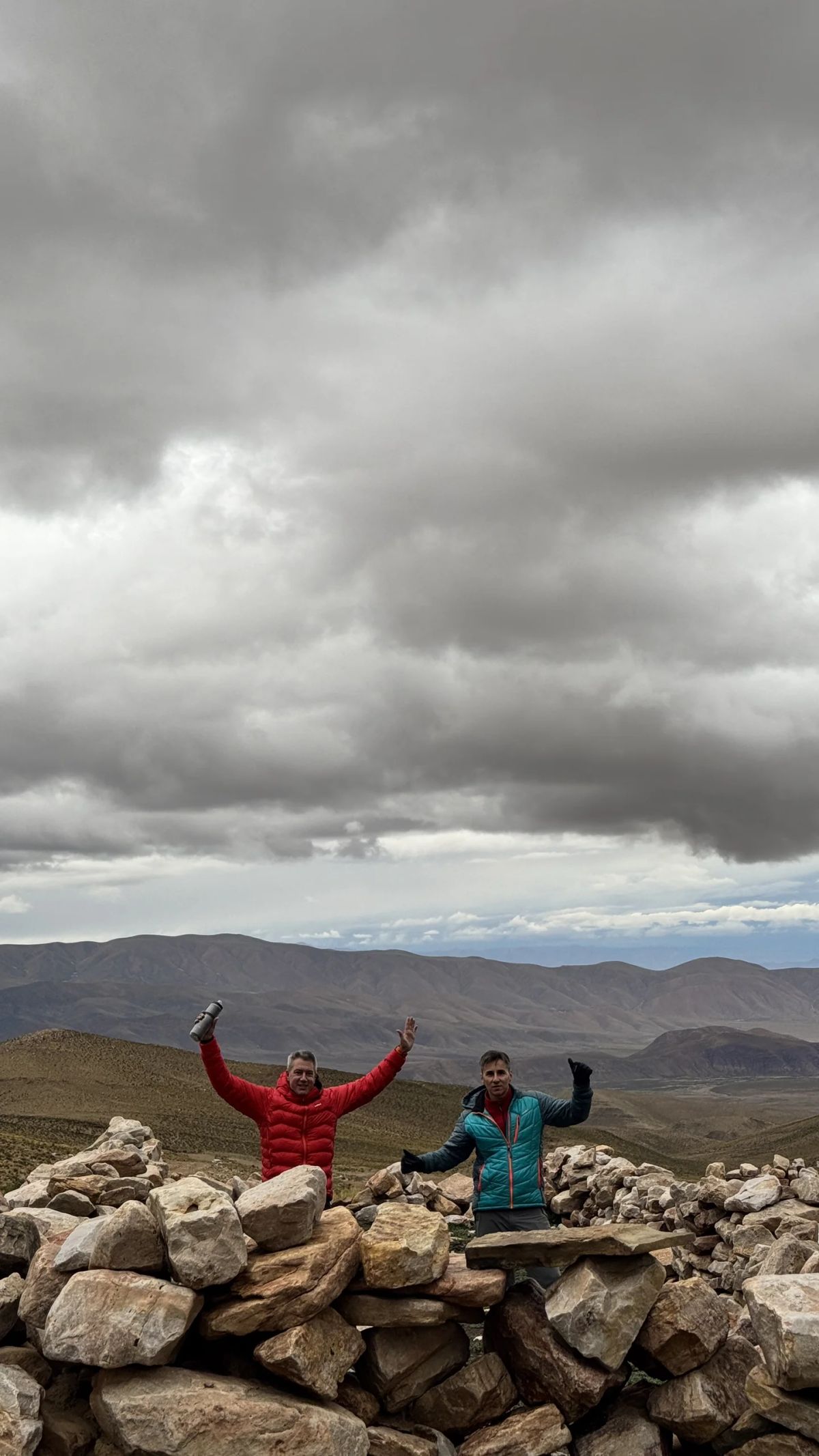 Dos integrantes del equipo festejando sobre un pircado de piedra en la altura