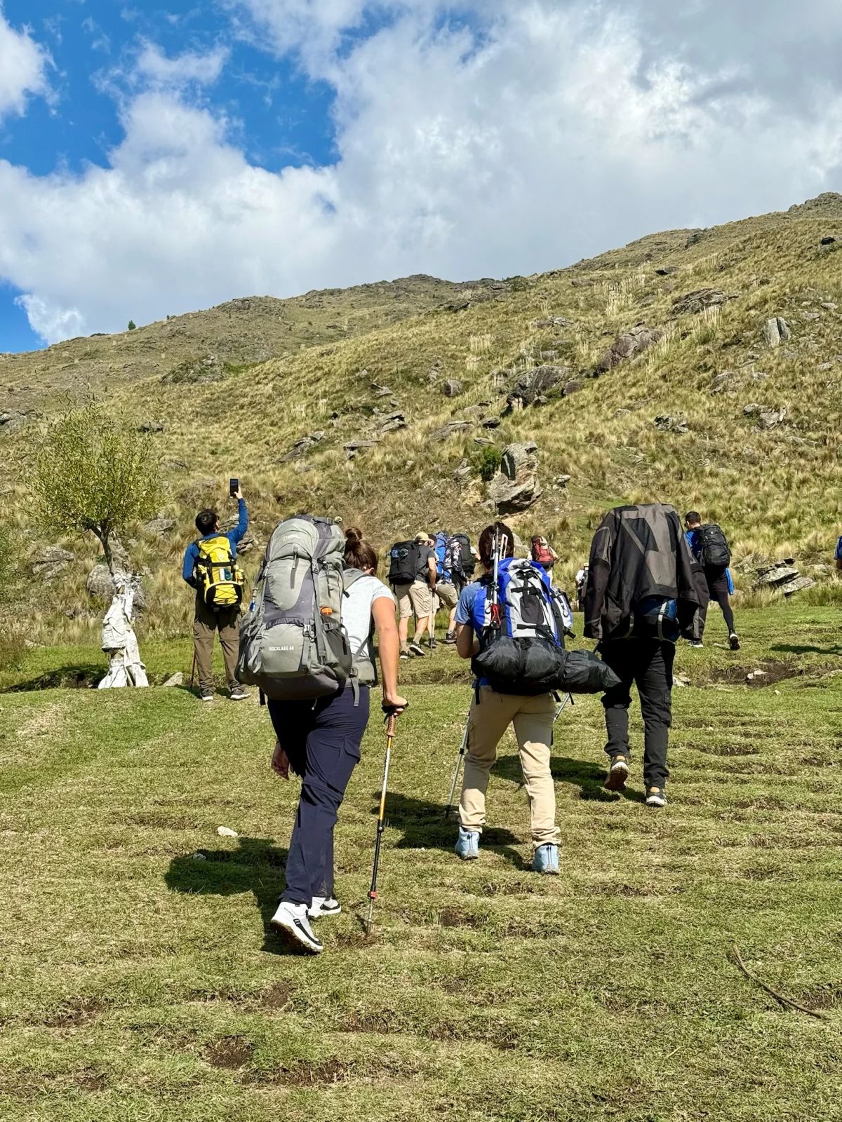Trekkers subiendo por la ladera de pastizal con mochilas de expedición rumbo al techo de Córdoba