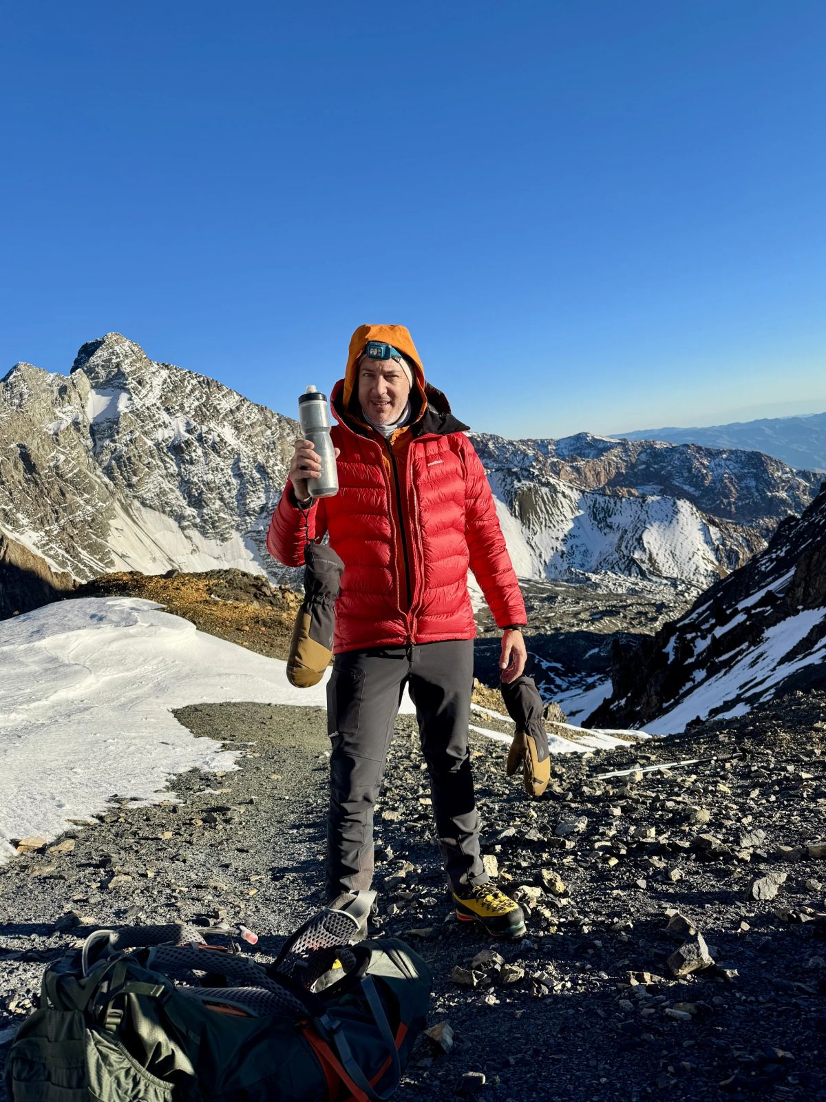 Andinista con campera de pluma al amanecer, listo para el día de ascenso