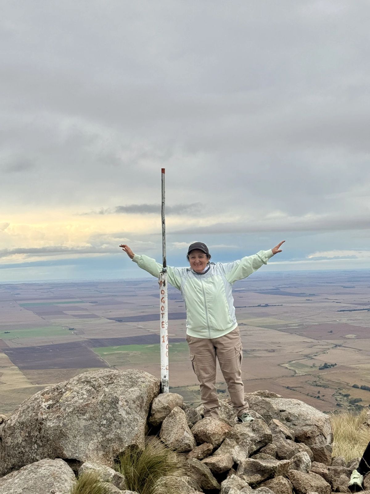 Participante junto al mástil de la cumbre con el cielo del atardecer puntano