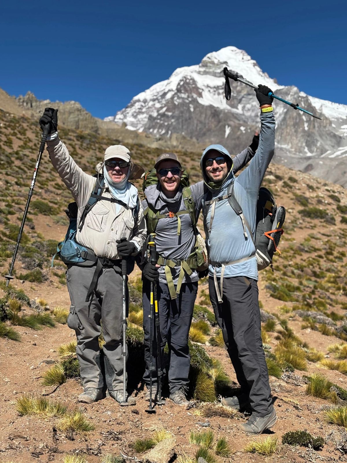 Los tres andinistas de Mons celebrando con el Aconcagua nevado detrás
