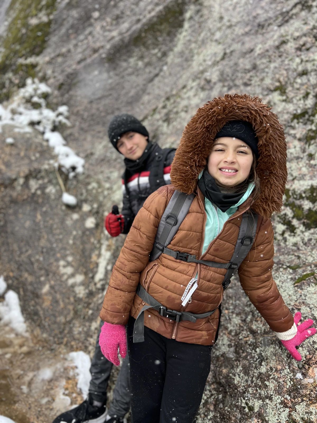 Participante con campera de piel sonriendo junto a una pared de granito nevada