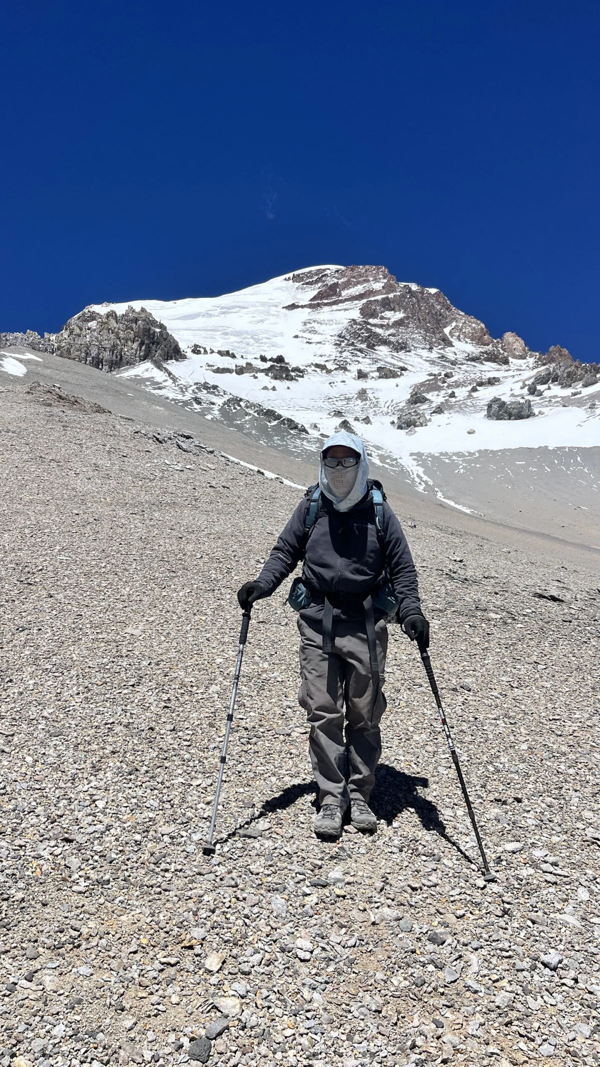 Andinista de porteo con mochila de expedición y el Aconcagua nevado detrás