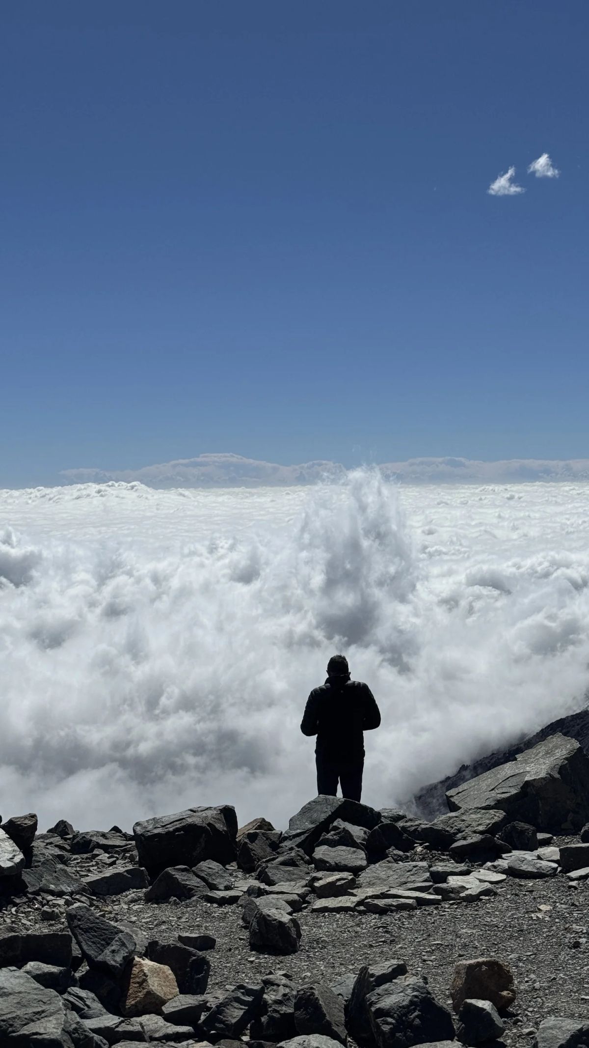 Andinista recortado contra el mar de nubes desde el campamento de altura