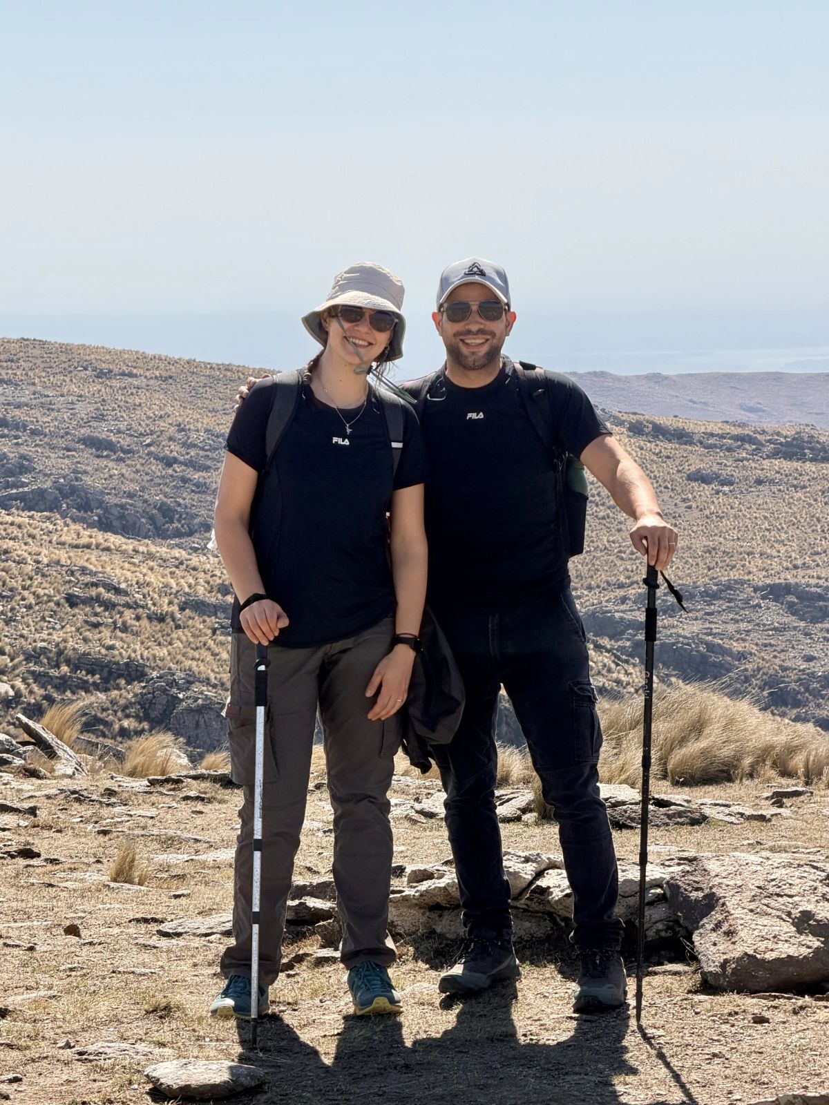 Dos trekkers posando en el filo de la sierra con el horizonte serrano detrás