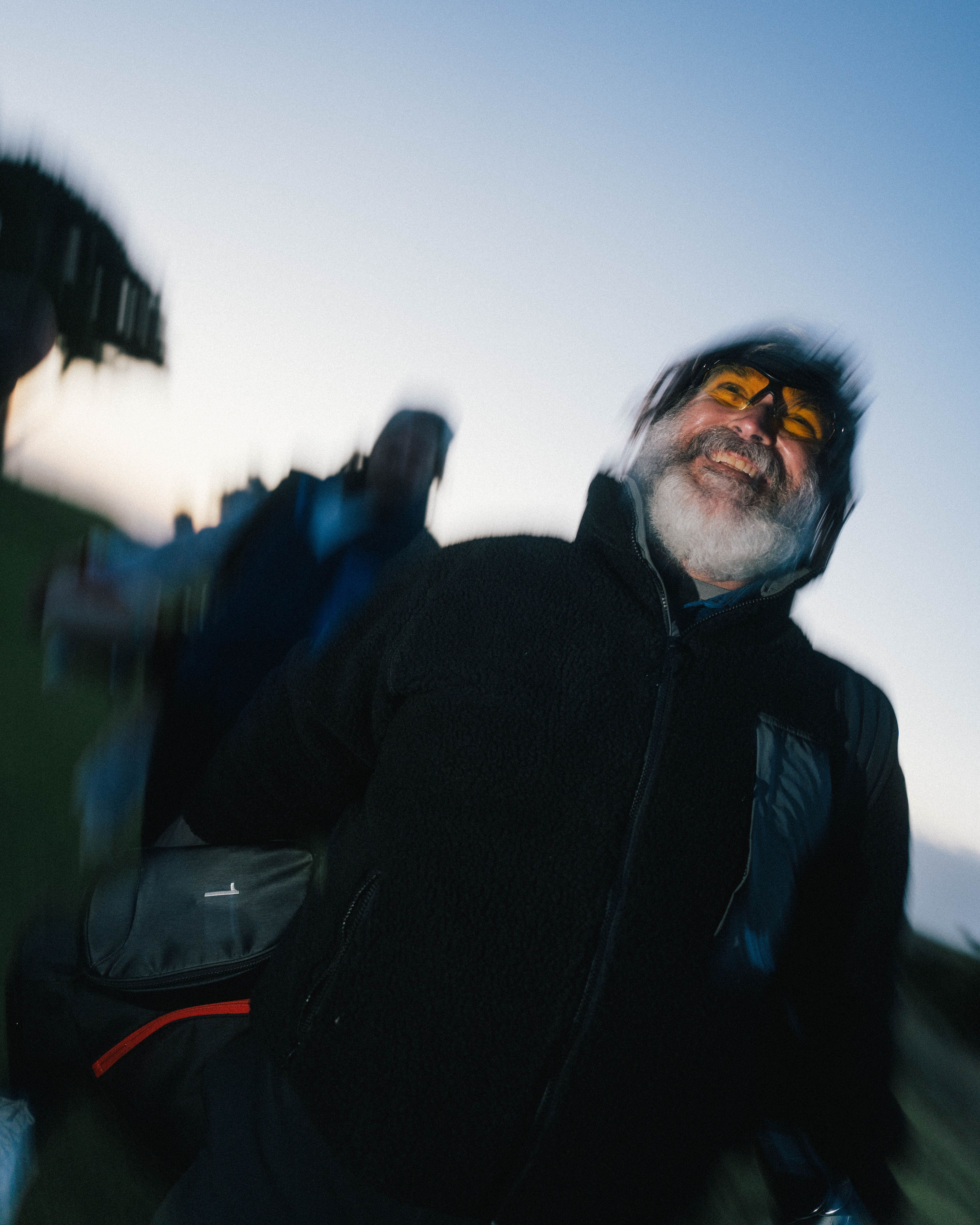 Bearded man in amber goggles laughing, captured with motion blur at dusk, Bandon Dunes