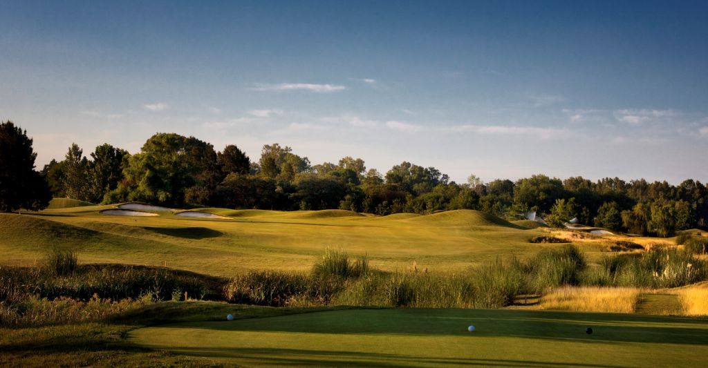 Buenos Aires Golf Club fairway framed by tall grasses and trees at golden hour