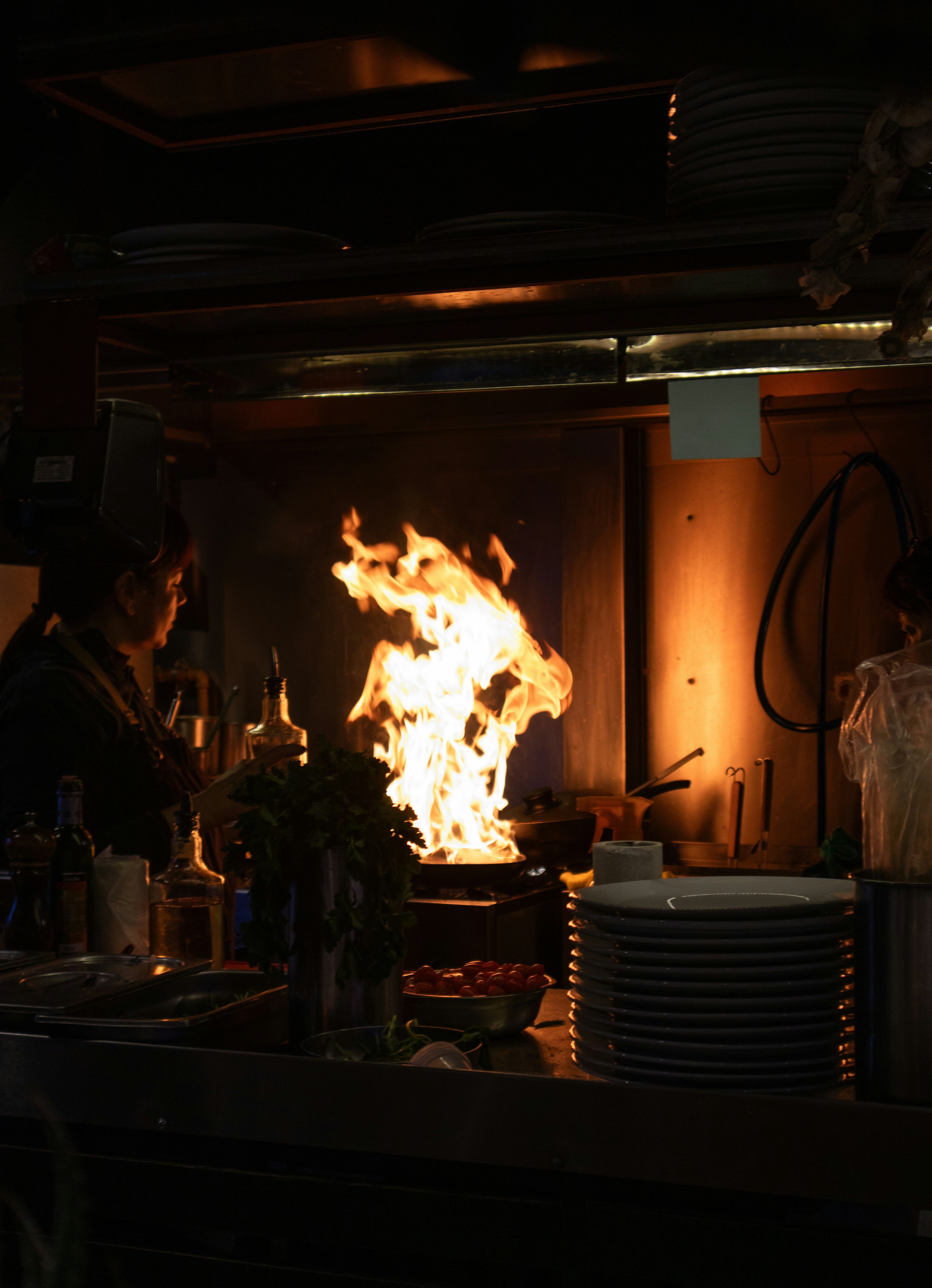 Chef tossing a flaming wok in a dimly lit restaurant kitchen