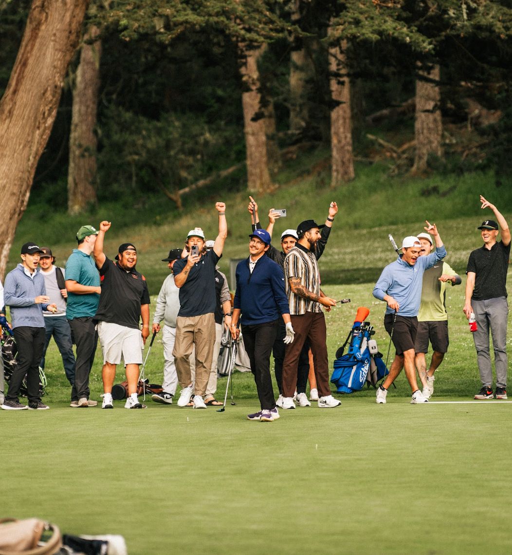 Golfers cheering and raising their arms around a player on a green