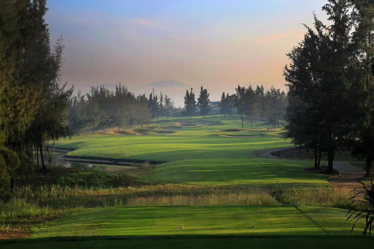 Tree-lined golf fairway with ponds at sunrise
