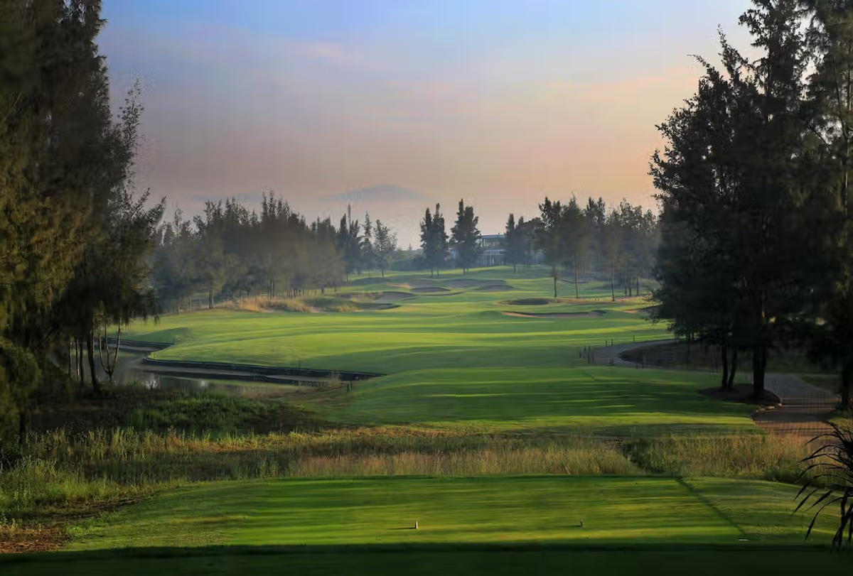 Tree-lined golf fairway with ponds at sunrise