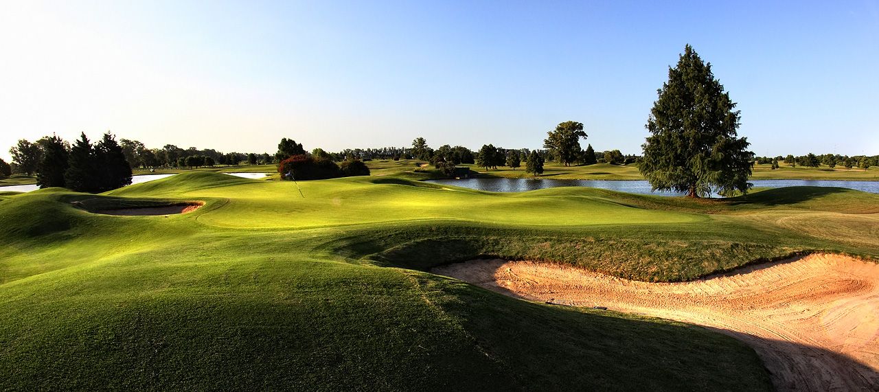 Rolling fairway with sand bunkers, lakes and tall trees at Pilar Golf