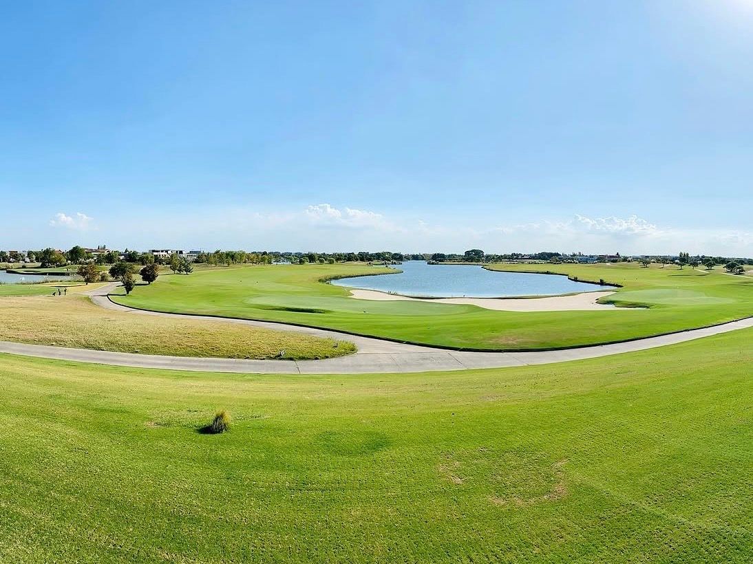 Panoramic view of Nordelta golf course with a lake and cart path