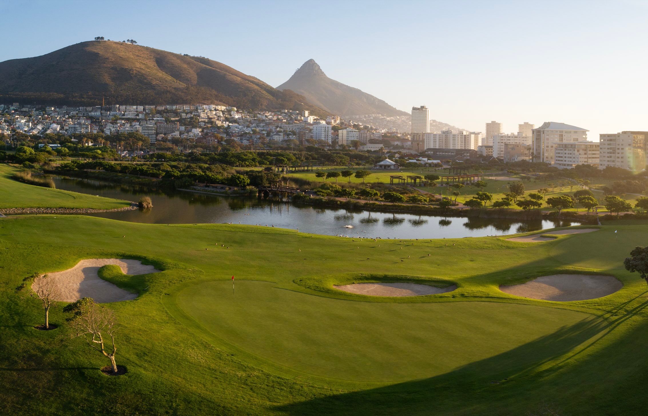 Metropolitan Golf Club green with bunkers and a pond, city and Lion's Head behind