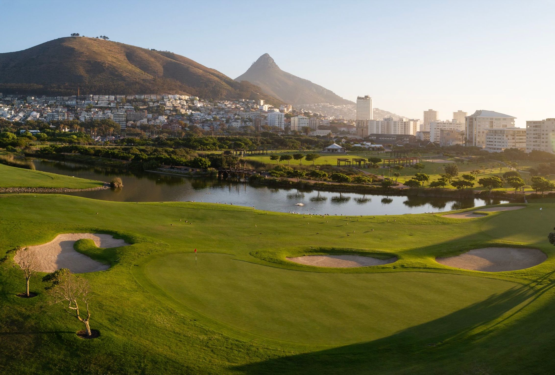 Metropolitan Golf Club green with bunkers and a pond, city and Lion's Head behind