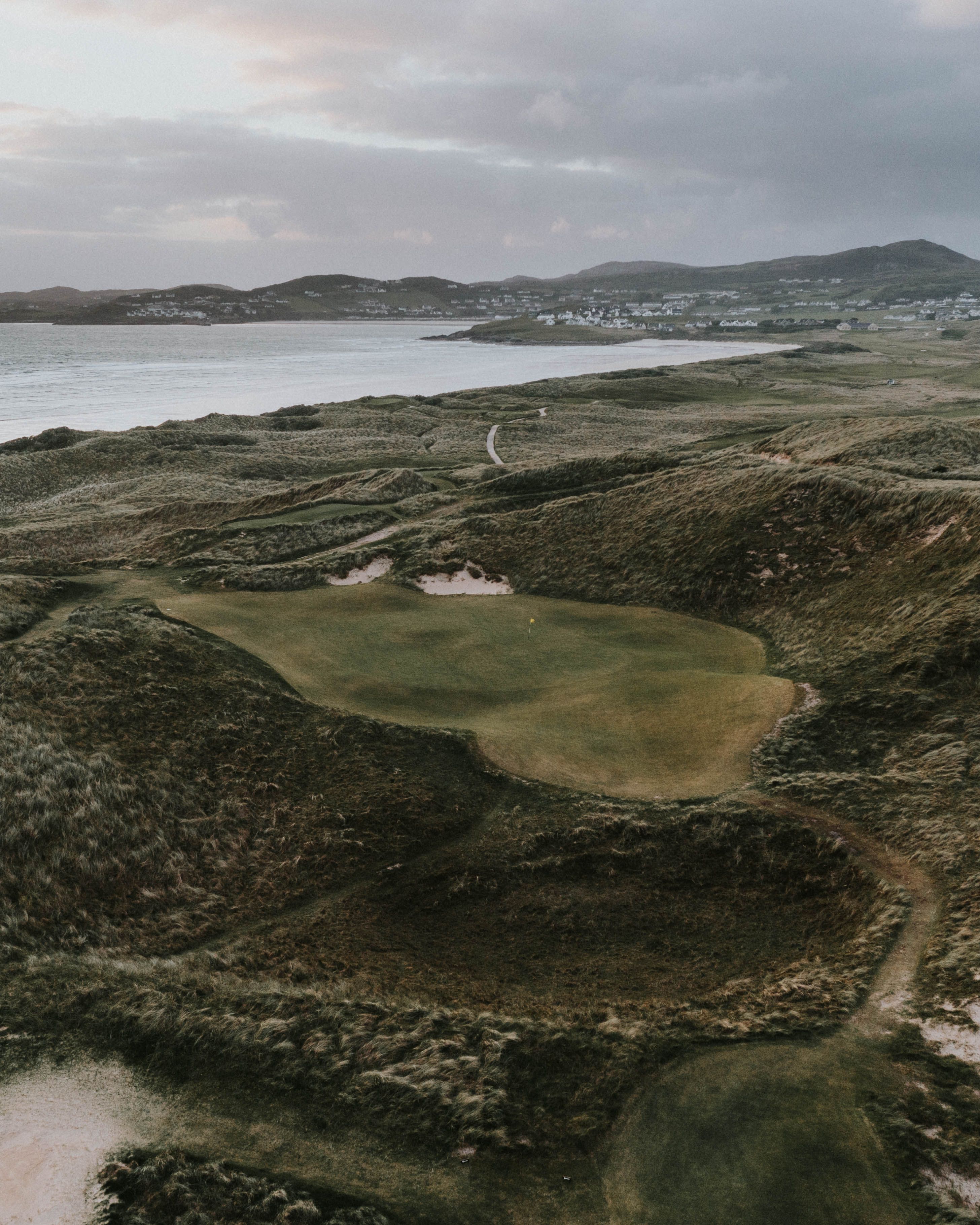 Aerial view of a green among dunes beside the sea at St Patrick's Links, Ireland