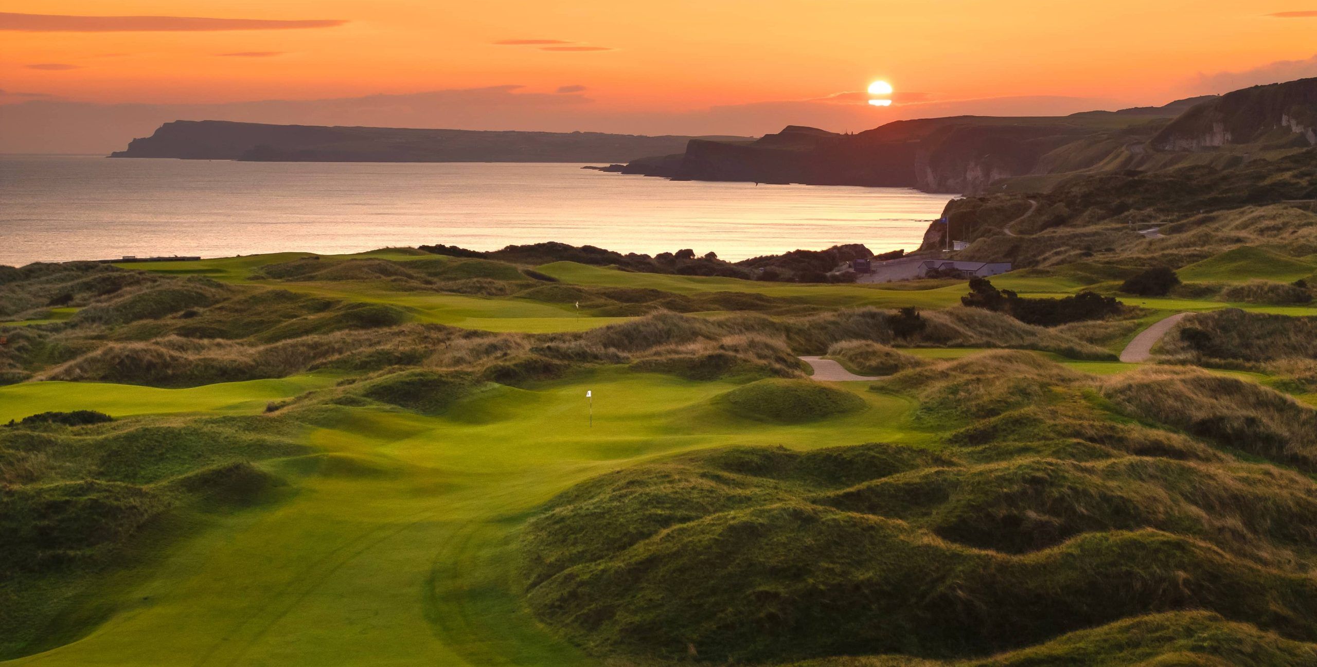 Sun setting over the sea beyond the rolling links fairways at Portrush, Northern Ireland